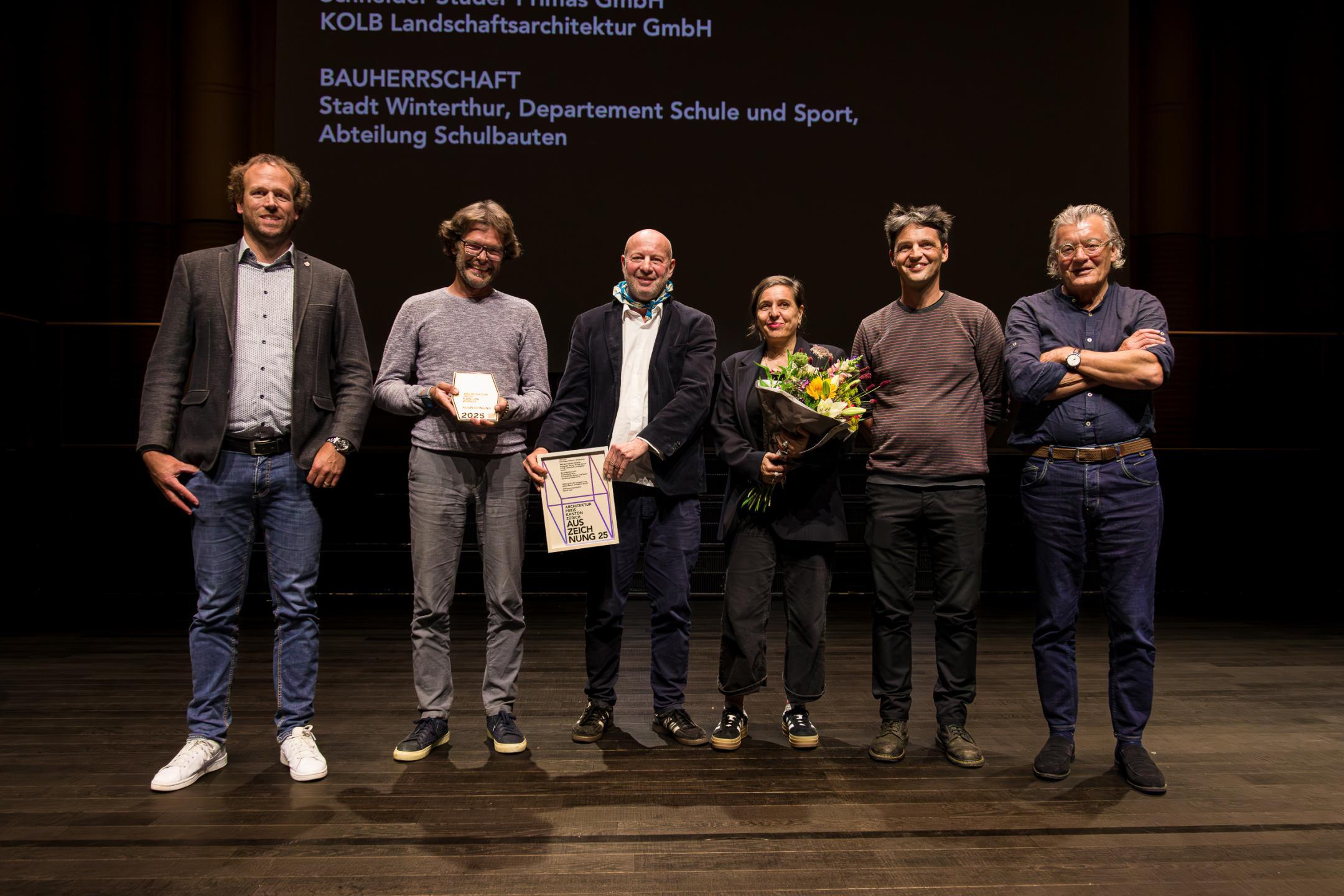 Die Preisträger posieren mit Blumenstrauss für das Foto.