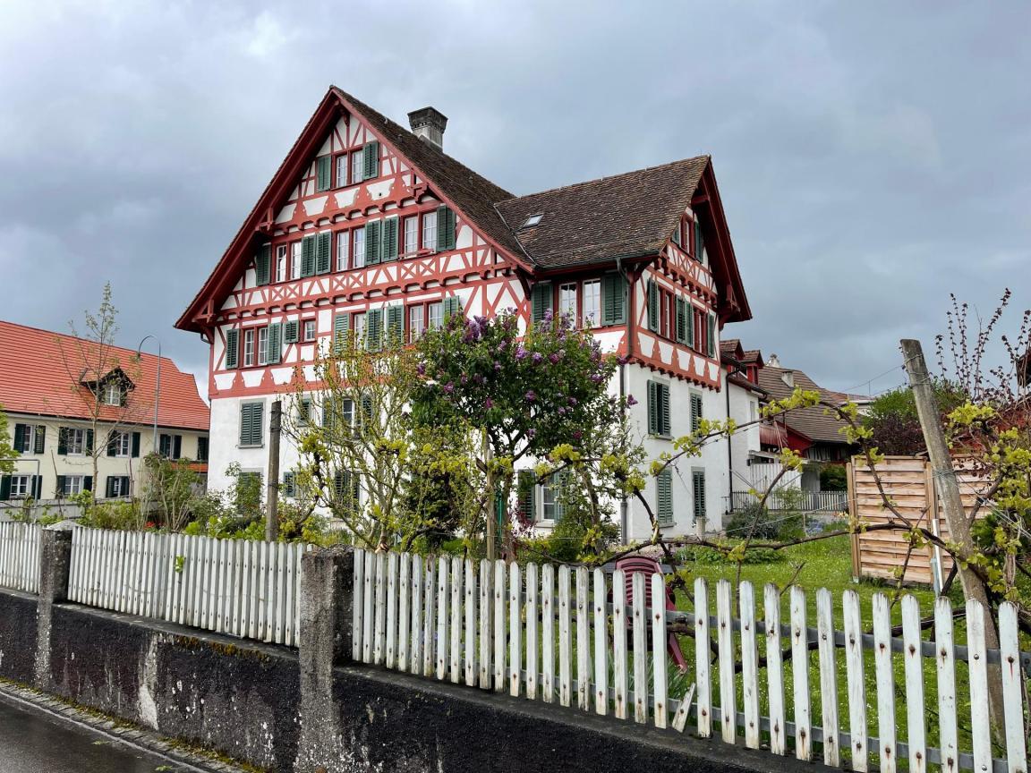 Historisches Wohnhaus umrandet von Garten und einem weissen Gartenzaun.