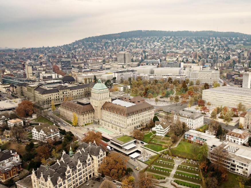 Blick von oben auf das künftige Hochschulgebiet Zürich Zentrum mit der Universität, der ETH und dem Universitätsspital Zürich sowie Grünflächen, im Hintergrund ist der Zürichberg zu sehen.