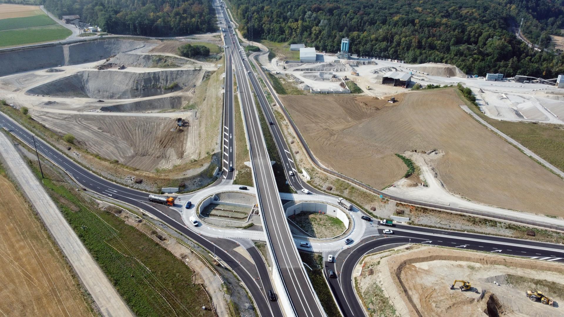 Bild von oben auf eine Strasseninfrastruktur mit einem erdnussförmigen Keisel und einer darüberführenden Brücke.