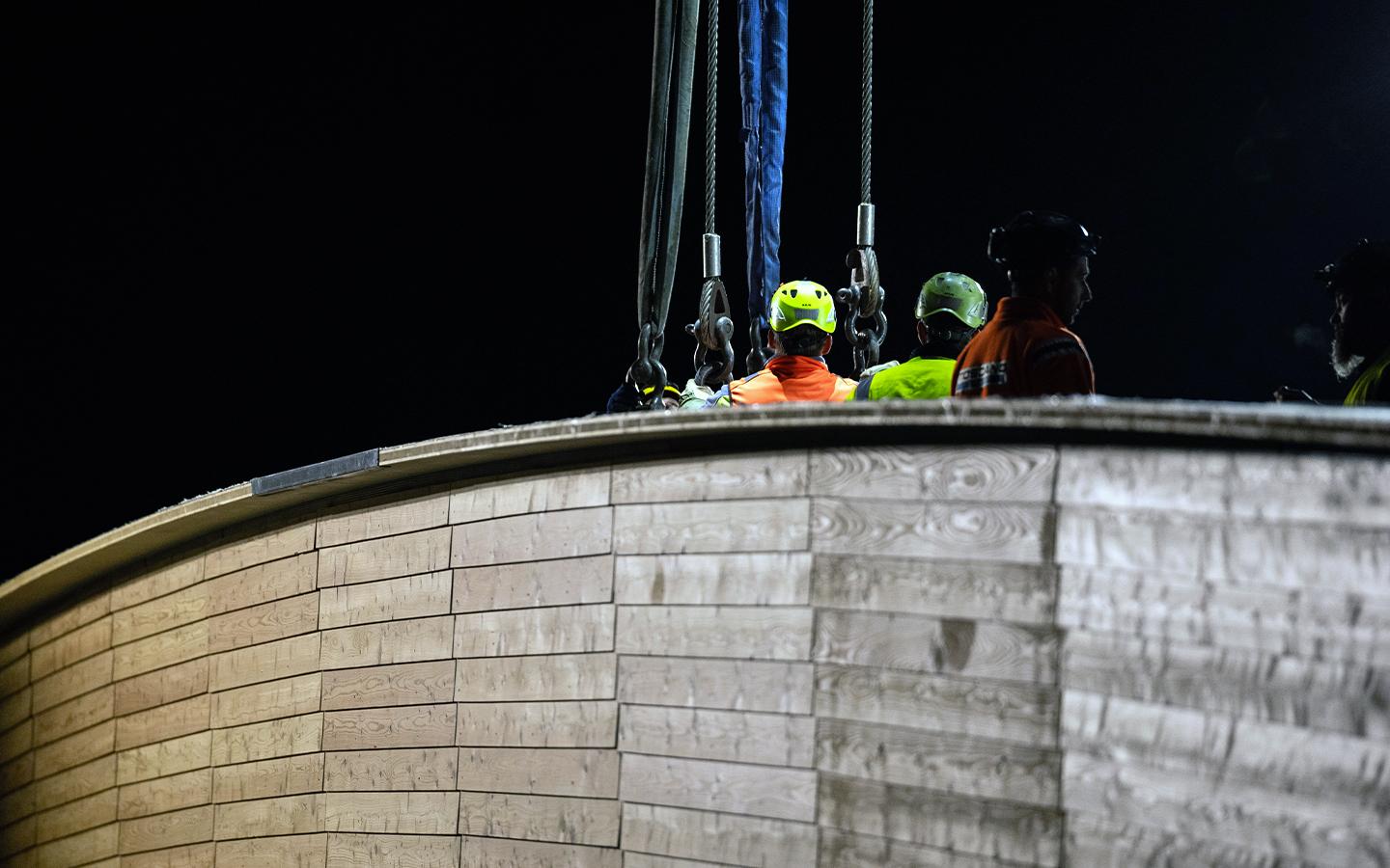 Detailaufnahme der Oberseite des Brückenelements. Man sieht die dicken Stahlseile und Ösen des Krans, an denen die Brücke hängt. 