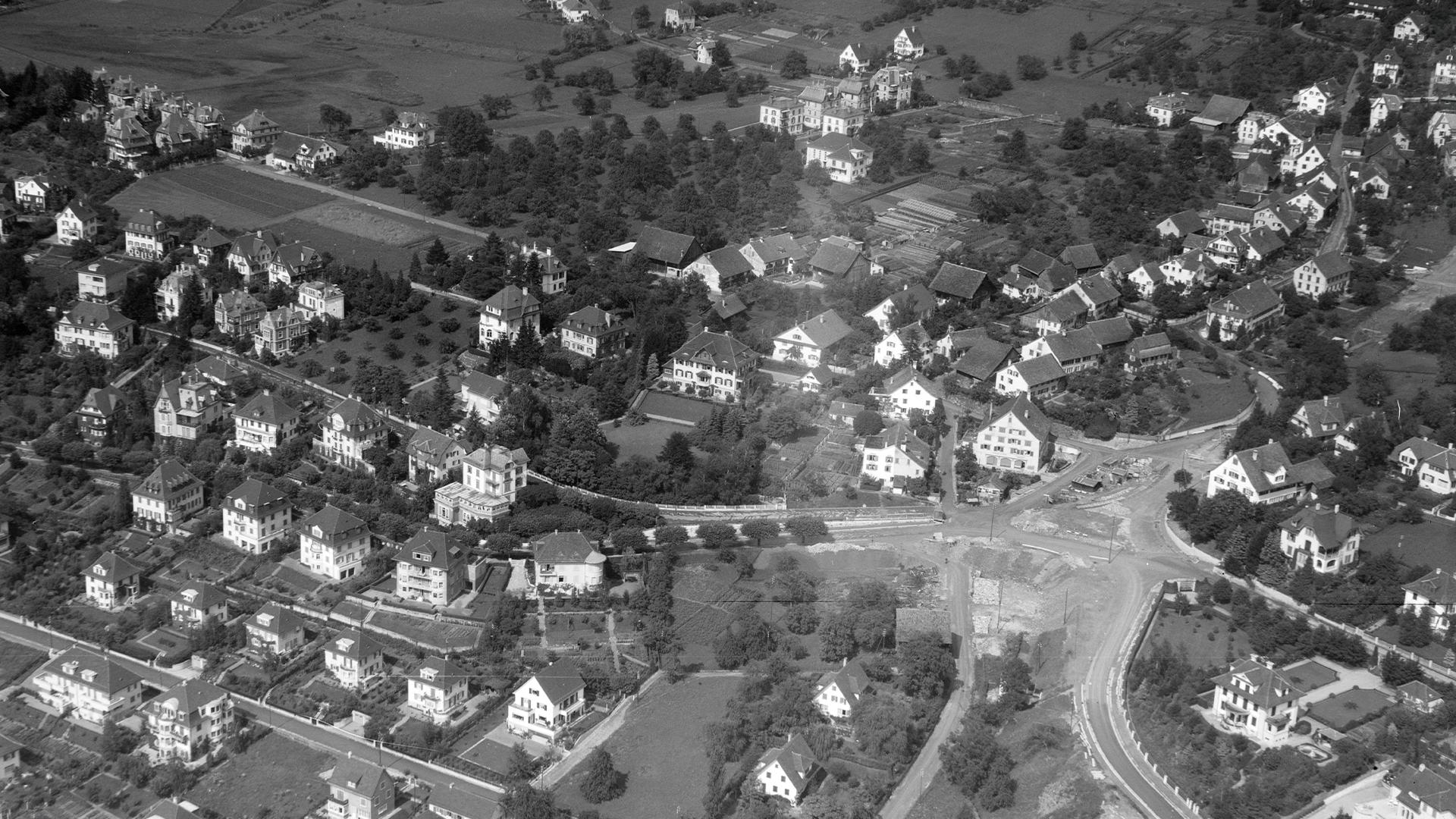 Historische Luftaufnahme von Zollikon, die die breite Siedlungsstruktur und den Dufourplatz als Kreuzung zeigt.
