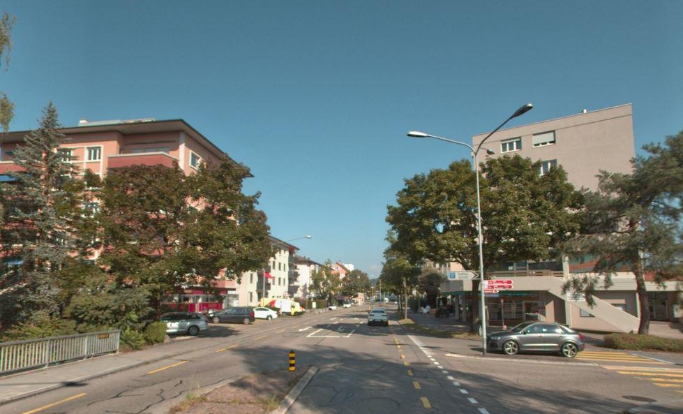 Die Schaffhauserstrasse in Kloten, mit Mittelinsel und Linksabbiegespur. Von rechts mündet eine Strasse in die Schaffhauserstrasse ein. 