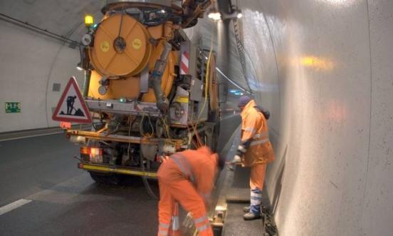 Zwei TBA-Mitarbeitende bei der Reinigung eines Kanals in einem Tunnel mit einem grossen Reinigungsfahrzeug