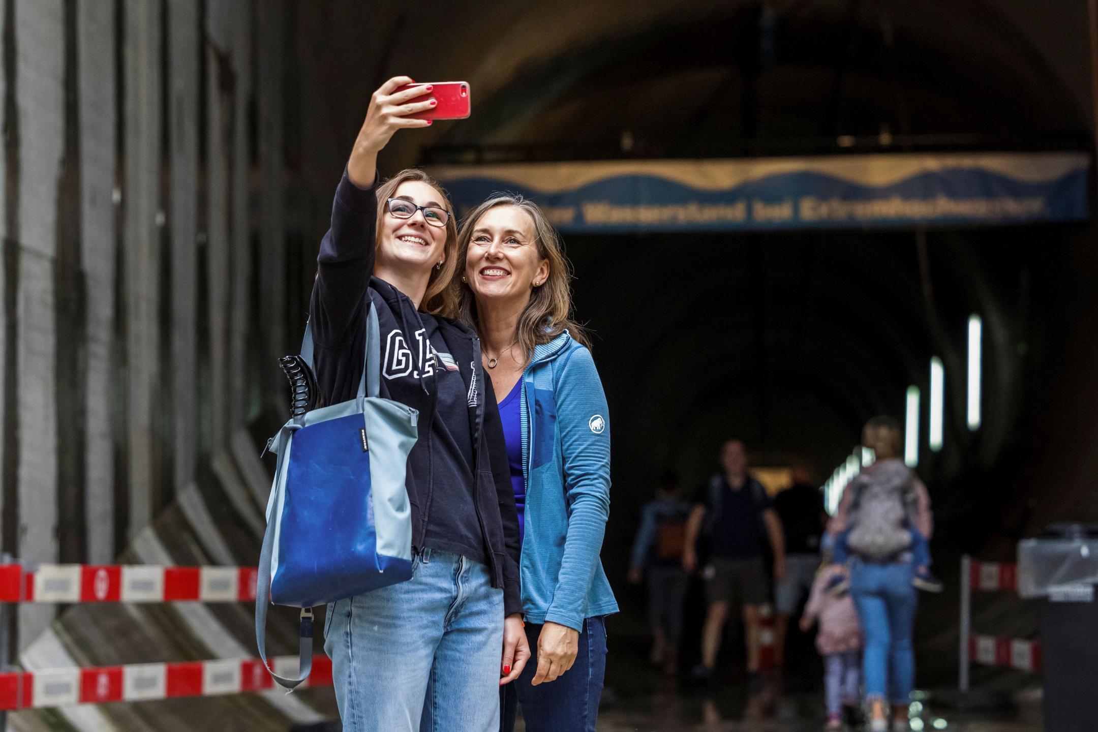 Zwei junge Frauen machen vor dem Stollen ein Selfie mit einem roten Handy.