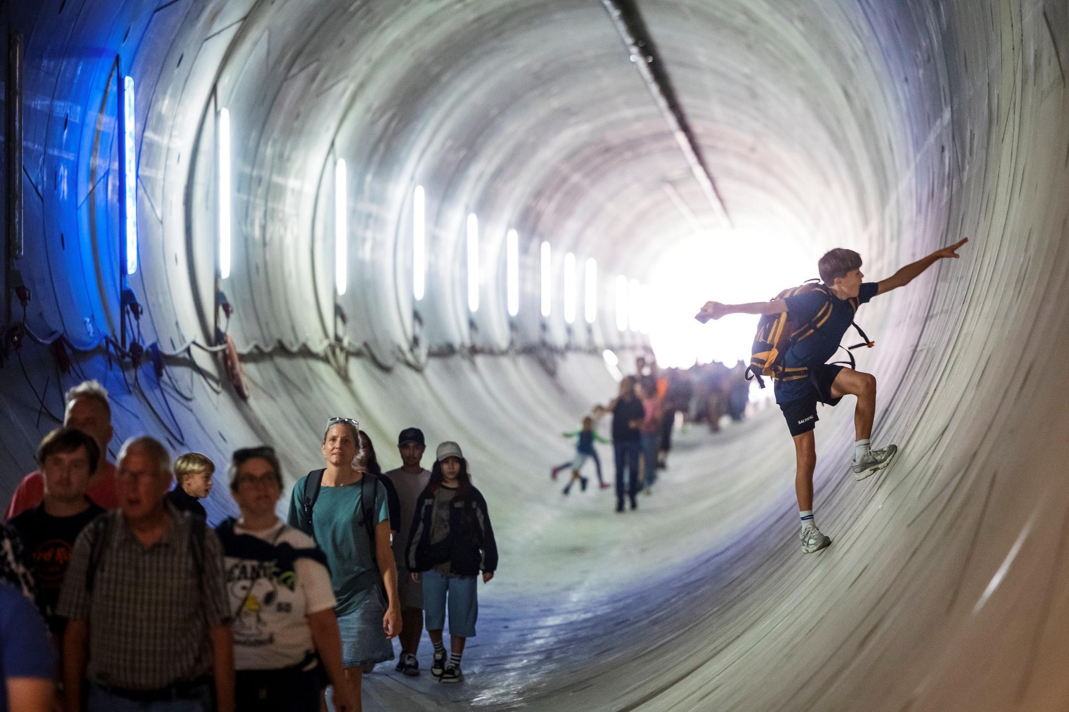 Leute im Stollen bei der Wanderung und ein Junge, der die Wand des Stollens in Turnschuhen besteigt und mit den Armen das Gleichgewicht ausbalanciert. 