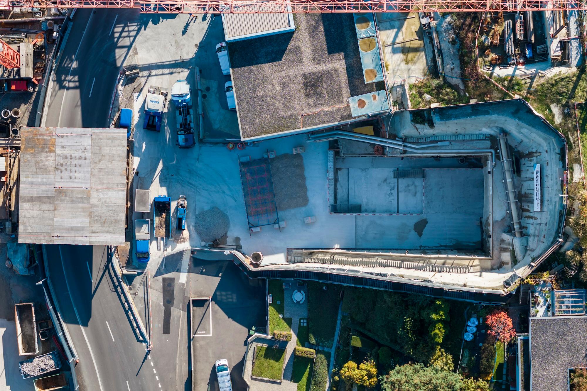 Drohnenaufnahme der Baustelle am Hang von Thalwil. Links die Strasse, oben angrenzend an die Baugrube das Dach der Abwasserreinigungsanlage.
