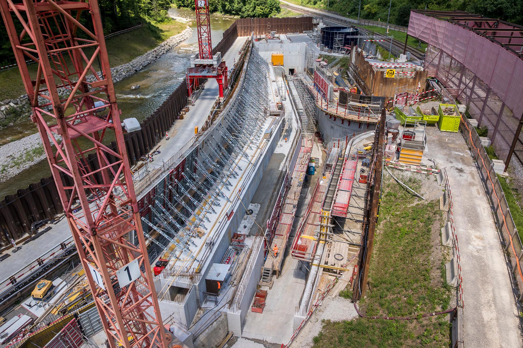 Drohnenaufnahme von der Baustelle des Einlaufbauwerks mit der Entstehung der Aussenwand und des Einlaufes sowie links der fliessenden Sihl zeigt.