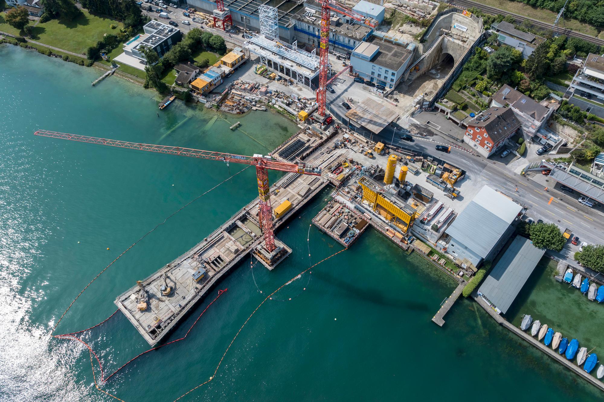 Luftaufnahme der Baustelle des Auslaufbauwerks. Am Seeufer befindet sich eine grosse Baustelle mit zwei Baukränen. 