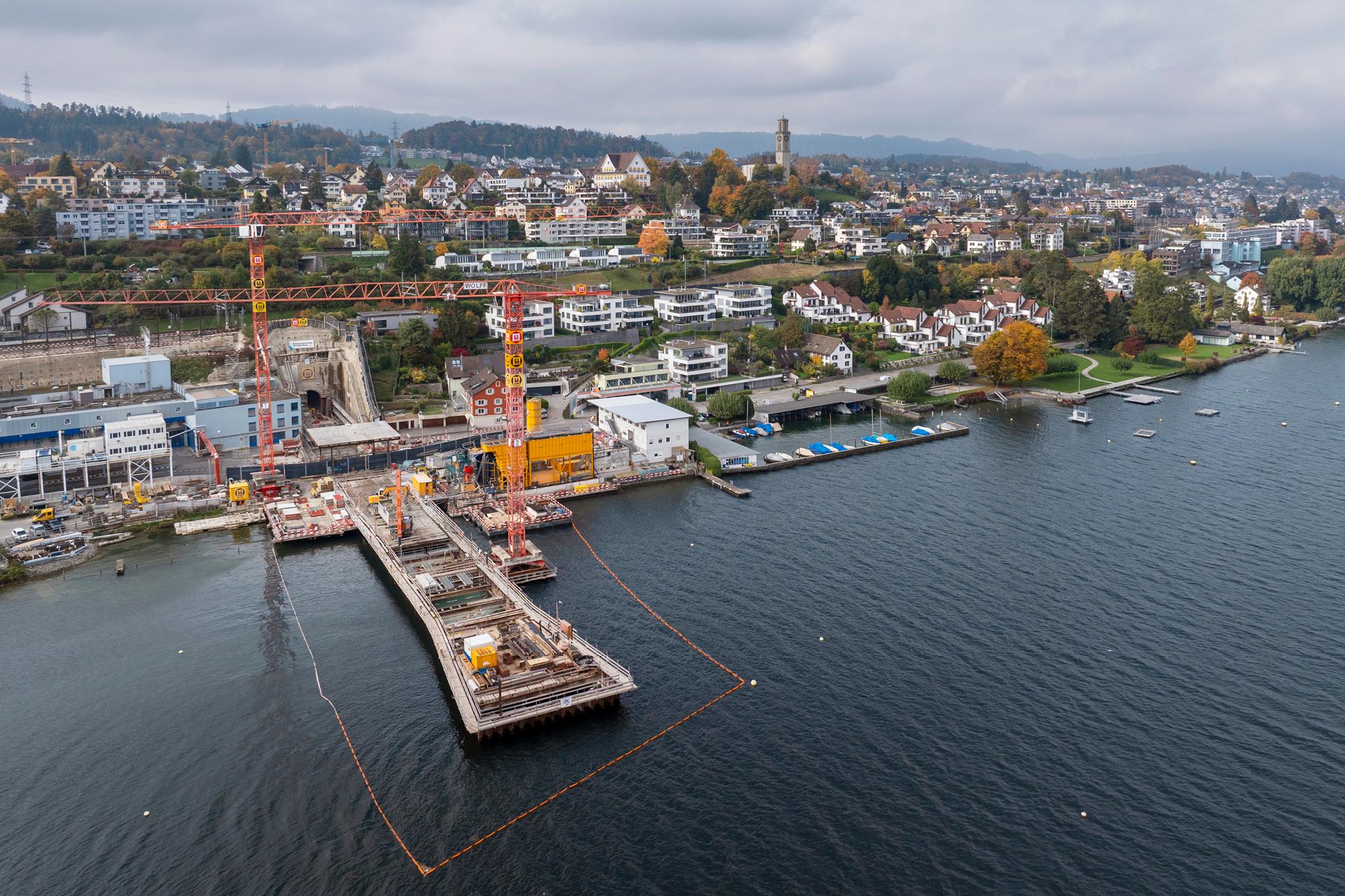 Luftaufnahme Richtung Thalwiler Seeufer mit der Baugrube im See und zwei Baukränen