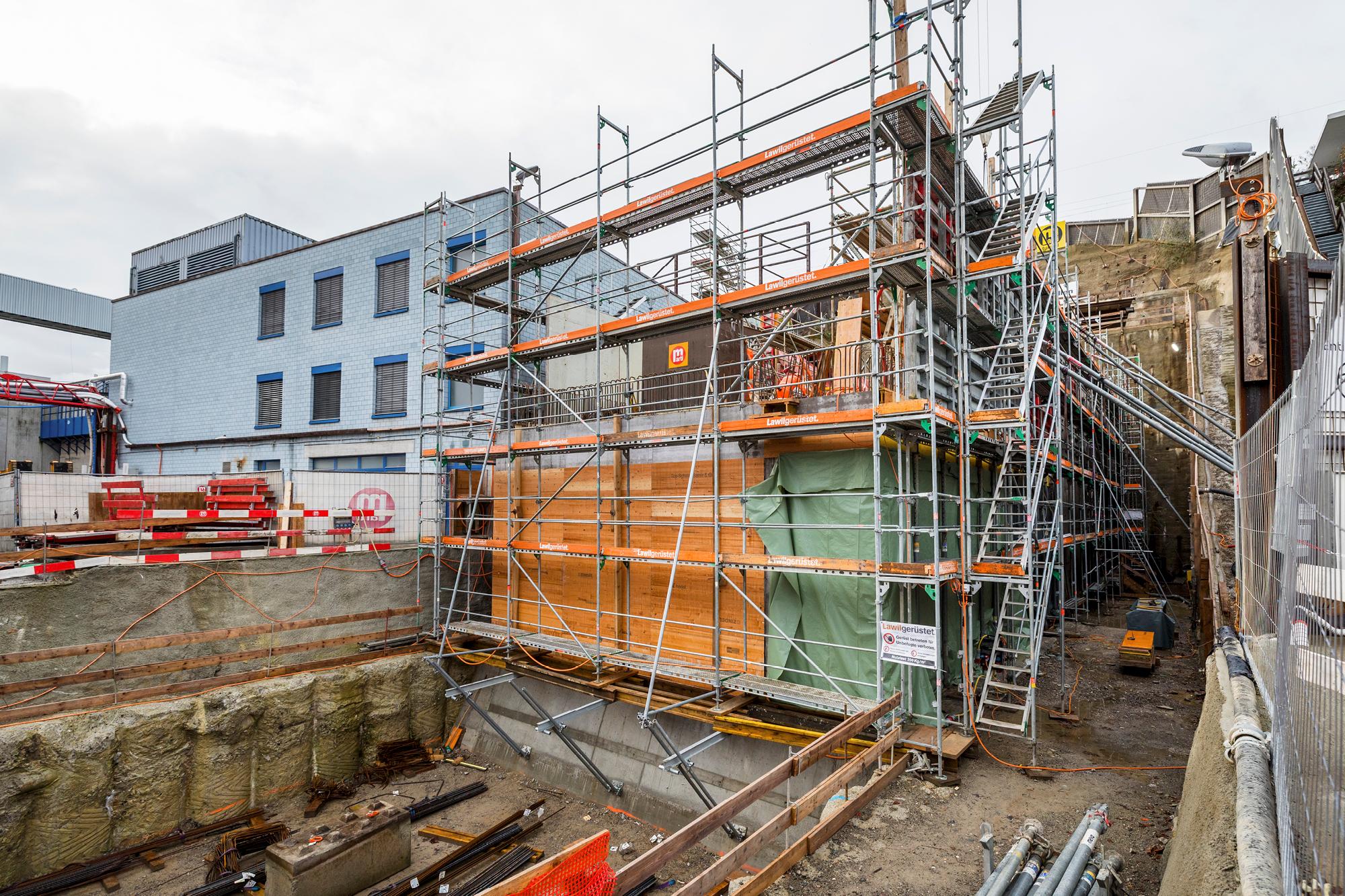 Baugerüst vor Betonwänden der Toskammer, daneben das benachbarte Gebäude der Abwasserreinigungsanlage