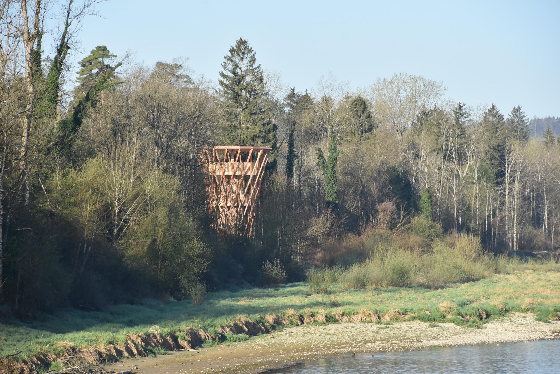 hölzerner Aussichtsturm am Flussufer, umgeben von Wald
