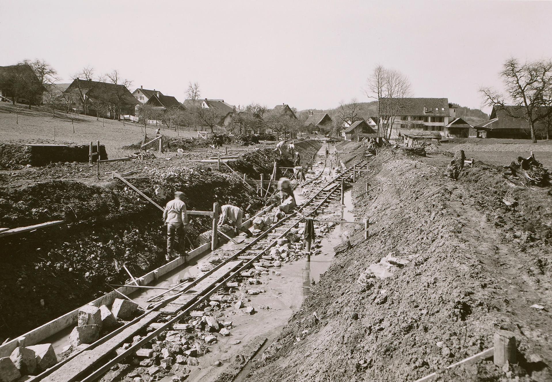 Die alte schwarz-weiss Aufnahme zeigt Männer bei der Arbeit am Flussbett.