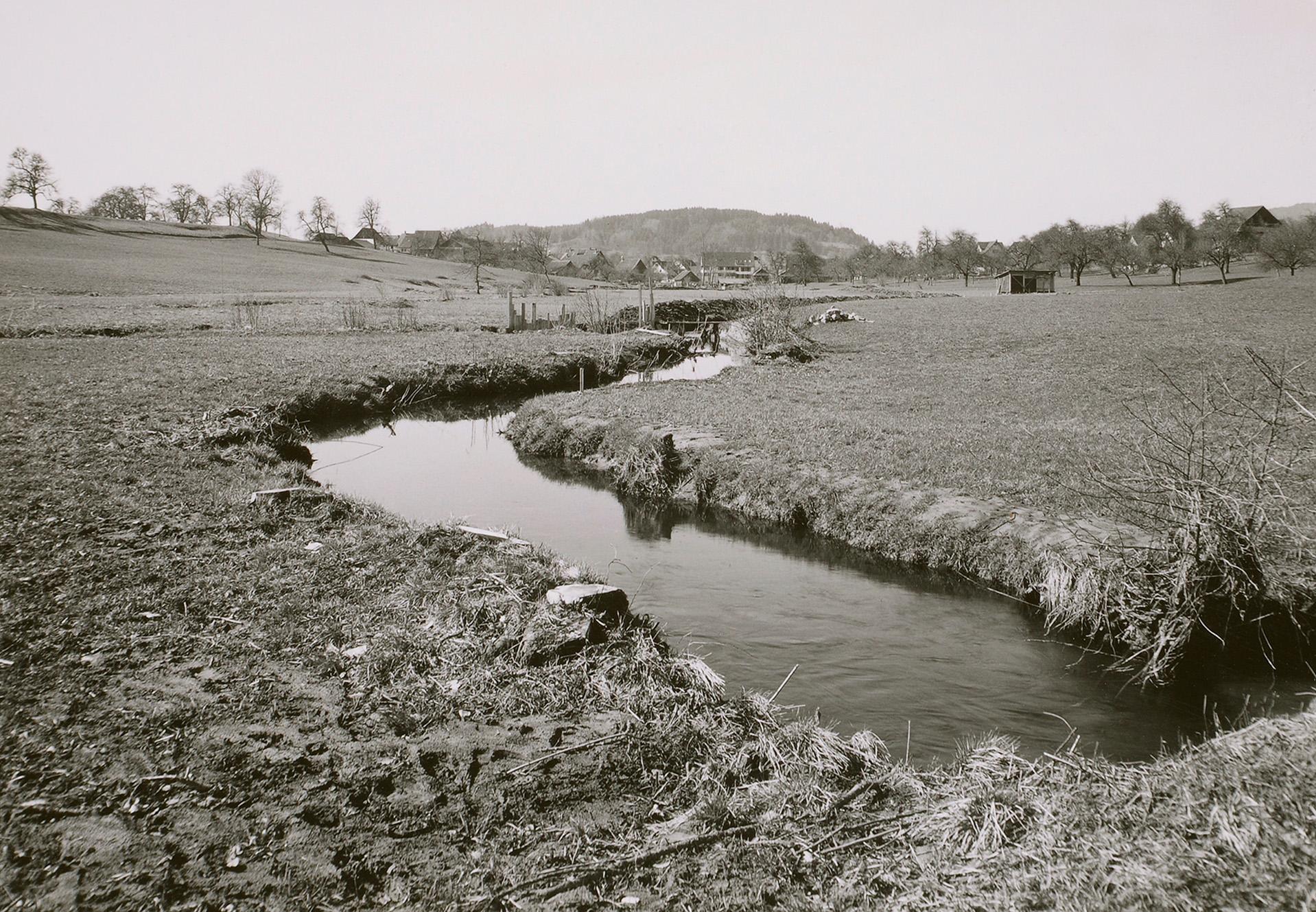 Ein altes schwarz-weiss Foto zeigt den begradigten Bachlauf der Jonen. 