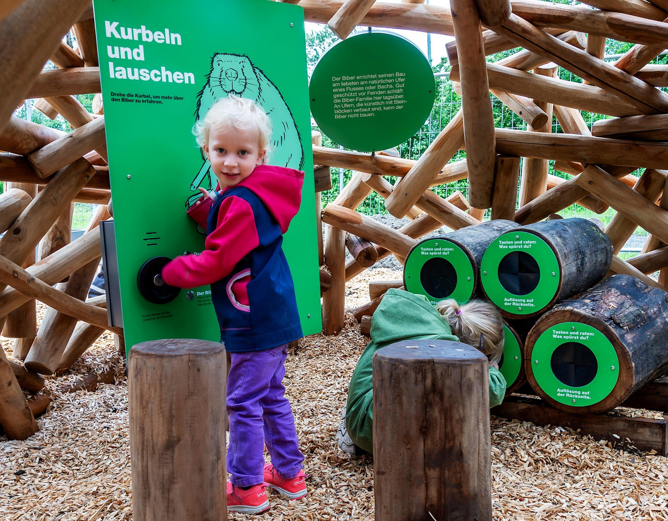 Ein kleines Kind dreht an einer Hörstation die Kurbel, um sie in Betrieb zu setzen.