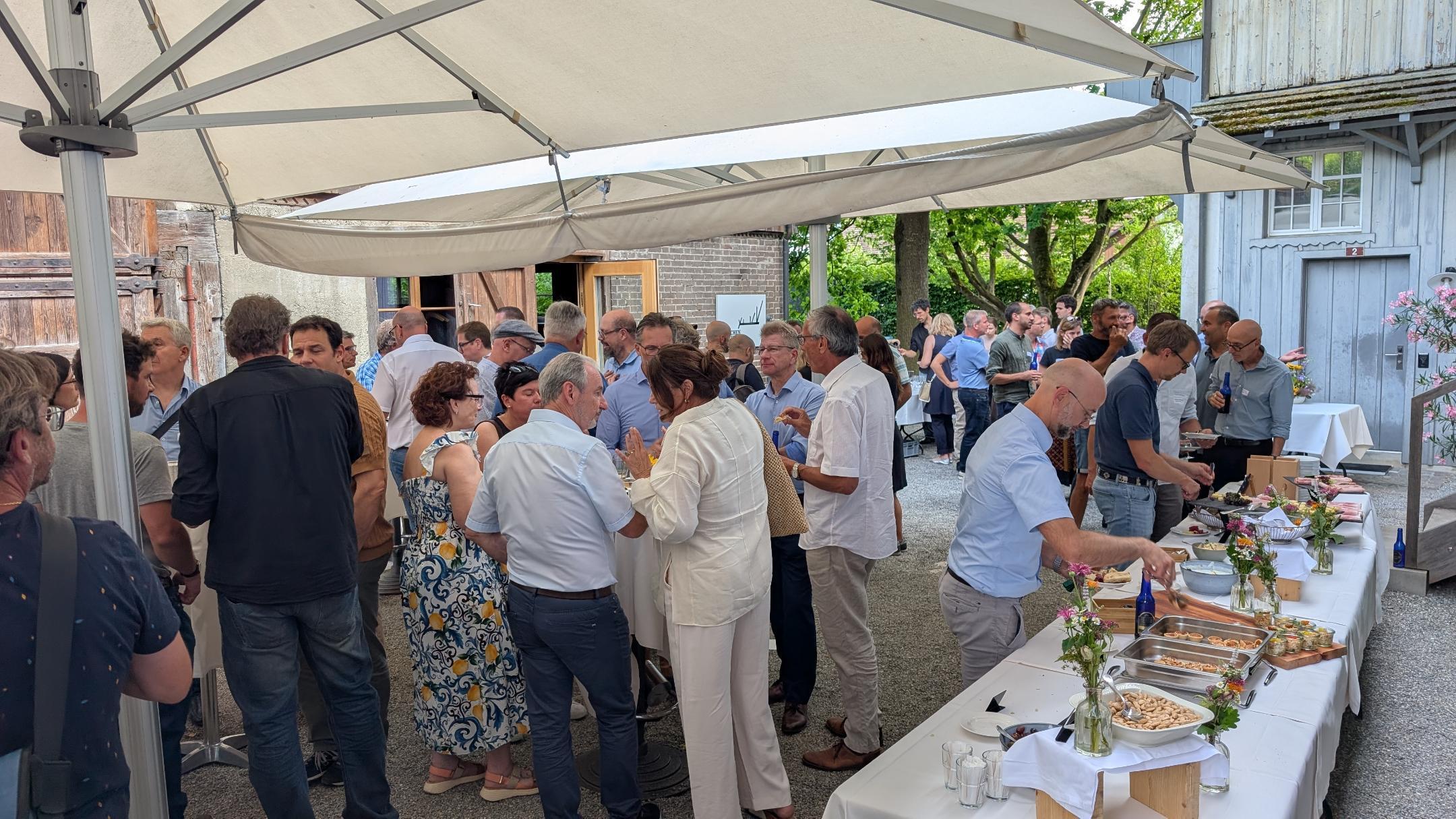 Eine Gruppe von rund 60 Menschen beim Apero in einem Hof.
