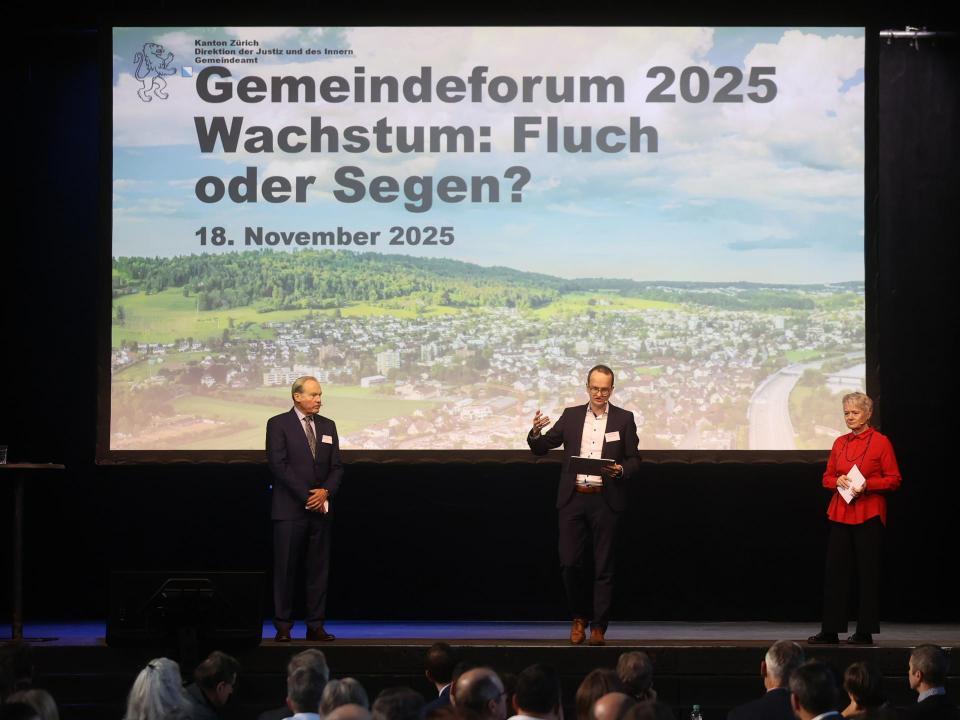 Drei Menschen stehen auf einer Bühne, im Hintergrund eine Leinwand mit dem Schriftzug «Gemeindeforum 2025 - Wachstum: Fluch oder Segen?»