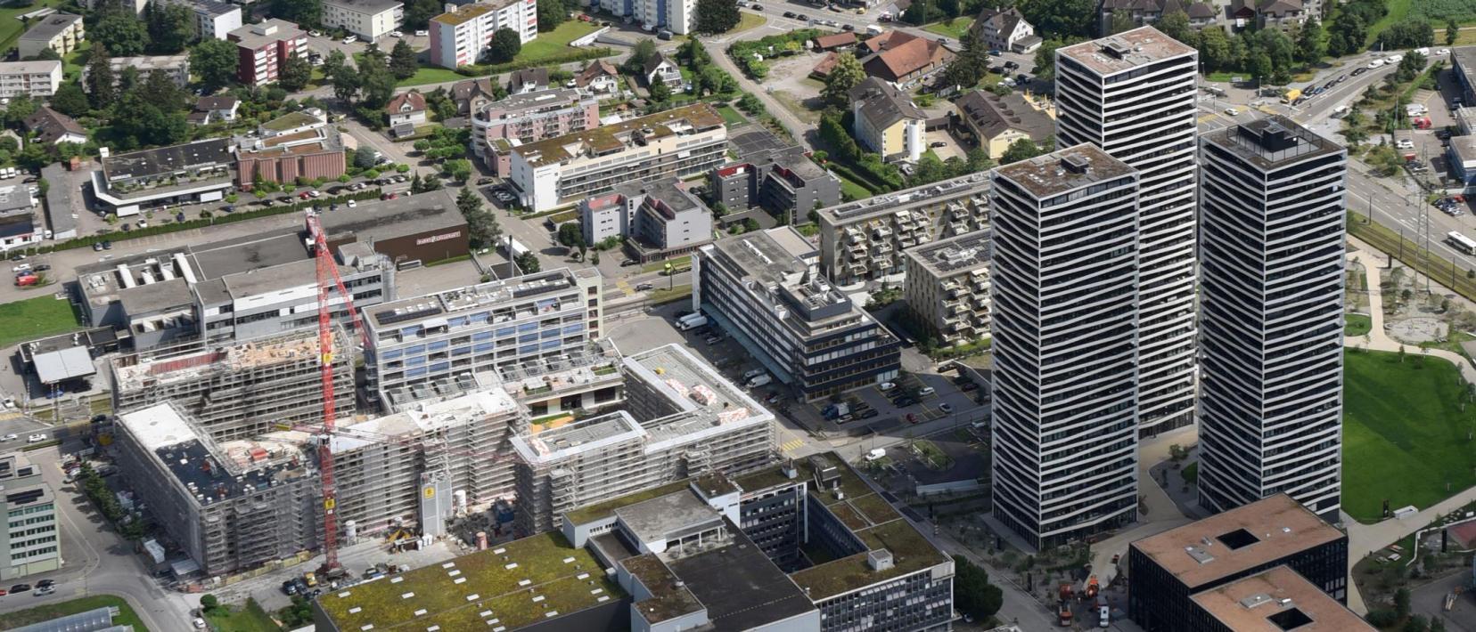 Urbanes Quartier mit drei Hochhäusern, ein Baukran verdeutlicht, dass das Quartier weiterentwickelt wird.