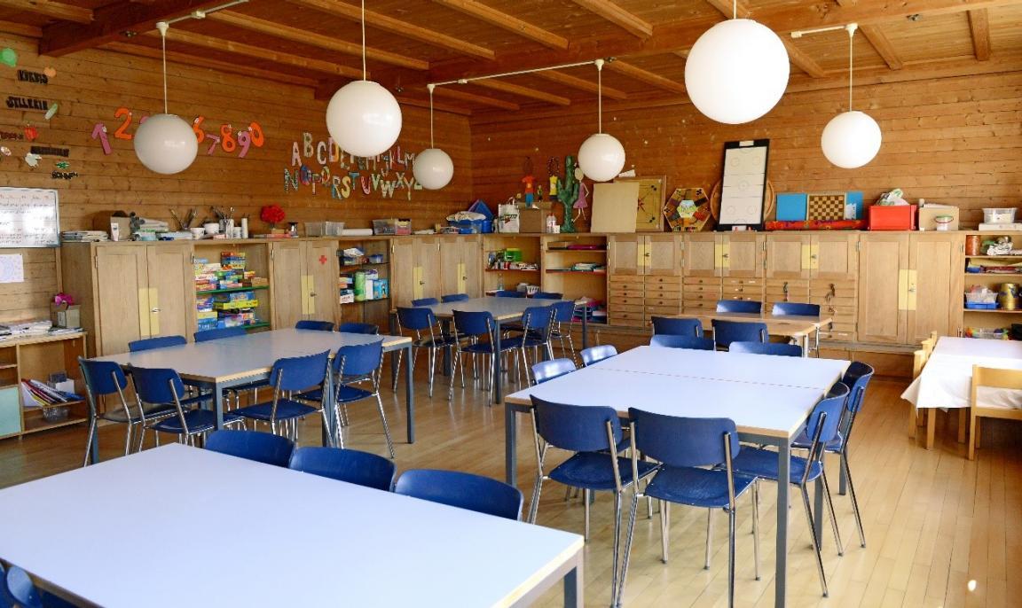 Blick in einen Schulhort mit Tischen und Spielzeug im Hintergrund