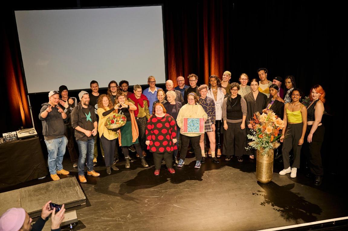 Die Ausgezeichneten, die Laudator/innen, Regierungsrätin Jacqueline Fehr und die Musiker von mix!t posieren auf der Bühne für ein Gruppenfoto.