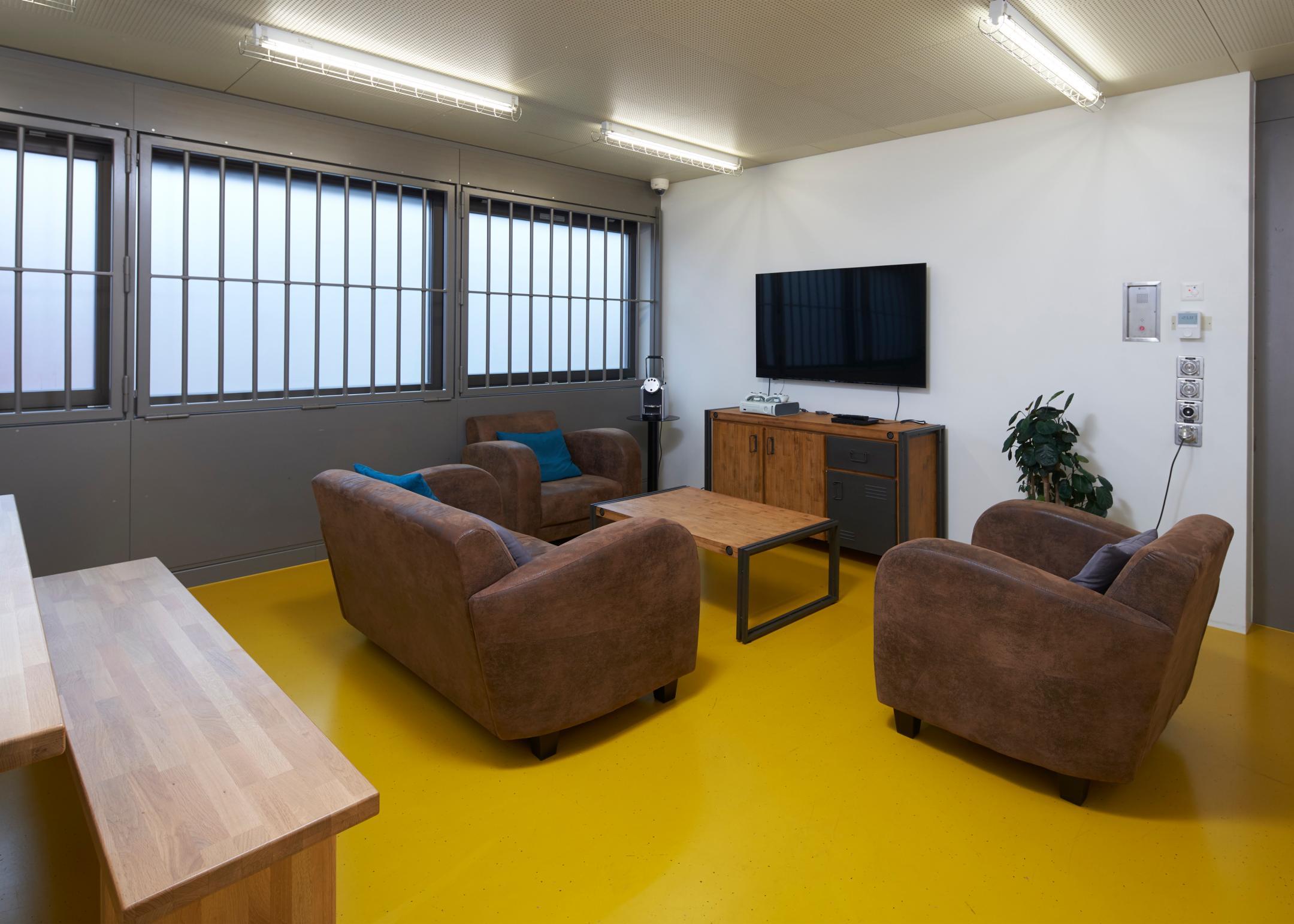 Zimmer mit Sofa, Sesseln, Tisch und Fernseher