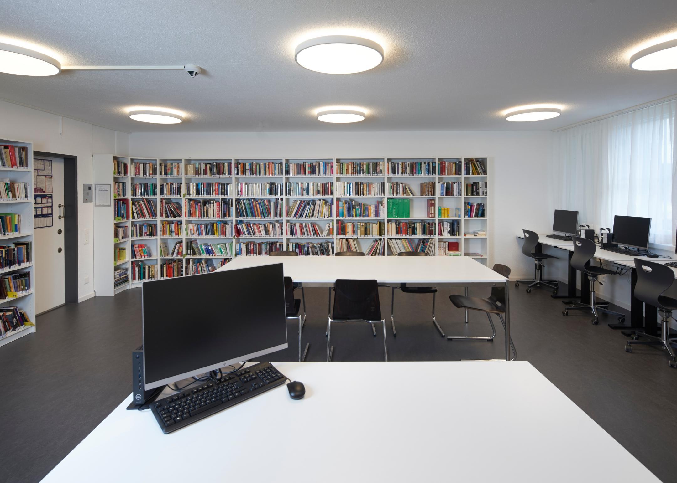 Regalen mit Büchern und Tische ausgestatten mit Computern