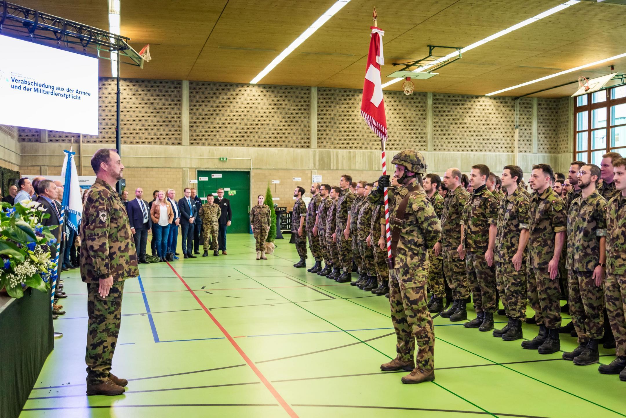 Kreiskommandant Daniel Bosshard steht gegenüber der Standarte im Beisein von Gästen und den zu Entlassenden.