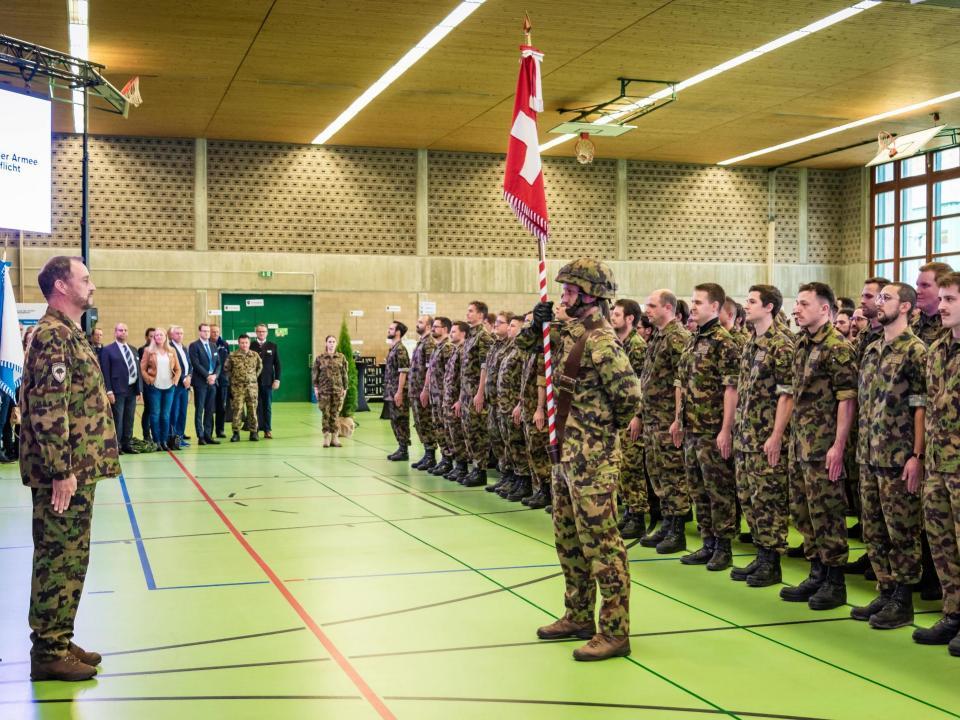 Kreiskommandant Daniel Bosshard steht gegenüber der Standarte im Beisein von Gästen und den zu Entlassenden.