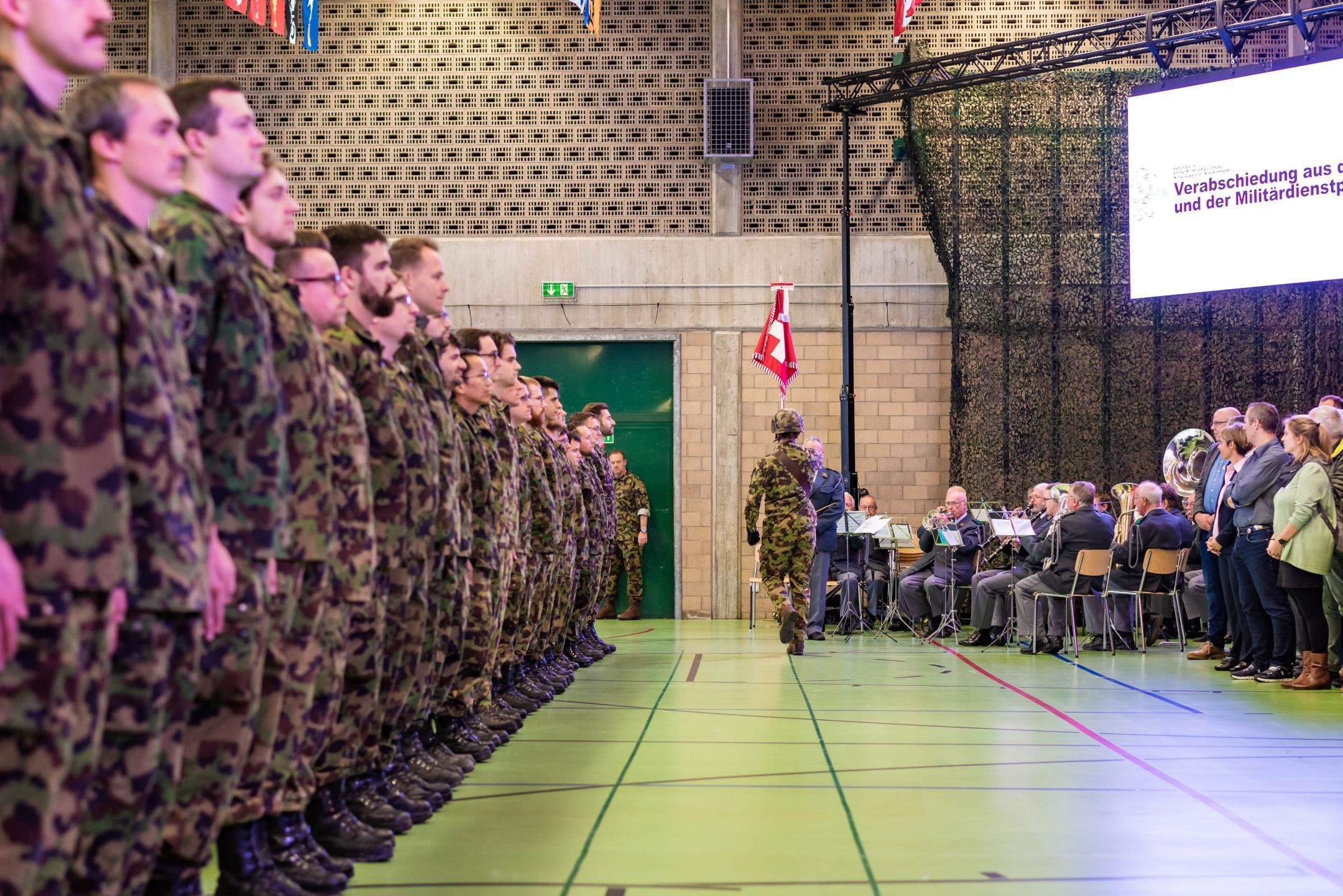 Entlassungsformation in Achtungsstellung beim Fahnenmarsch und der vorbeilaufenden Schweizerfahne mit Fähnrich