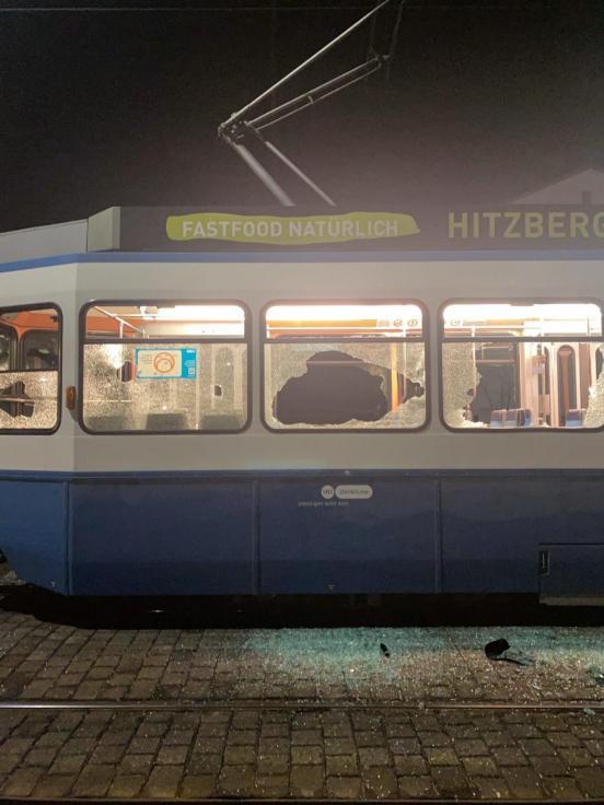 Foto eines VBZ Trams älterer Bauweise in dem alle Scheiben eingeschlagen und zerstört sind.