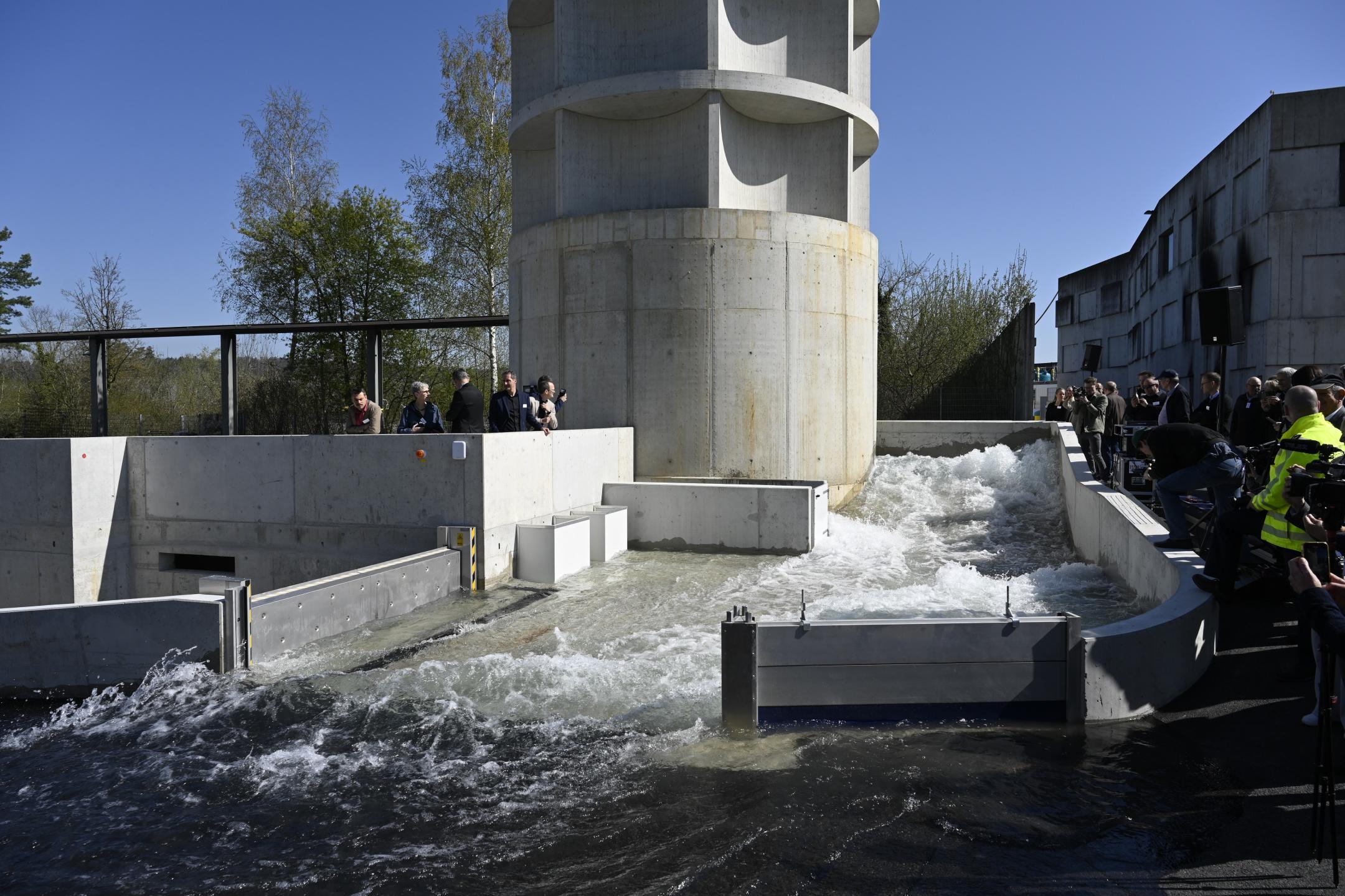 Einen Menschentraube steht rund um die Flutungsanlage und sieht eine Live-Demonstration. Das Wasser fliesst in Strömen hinunter..
