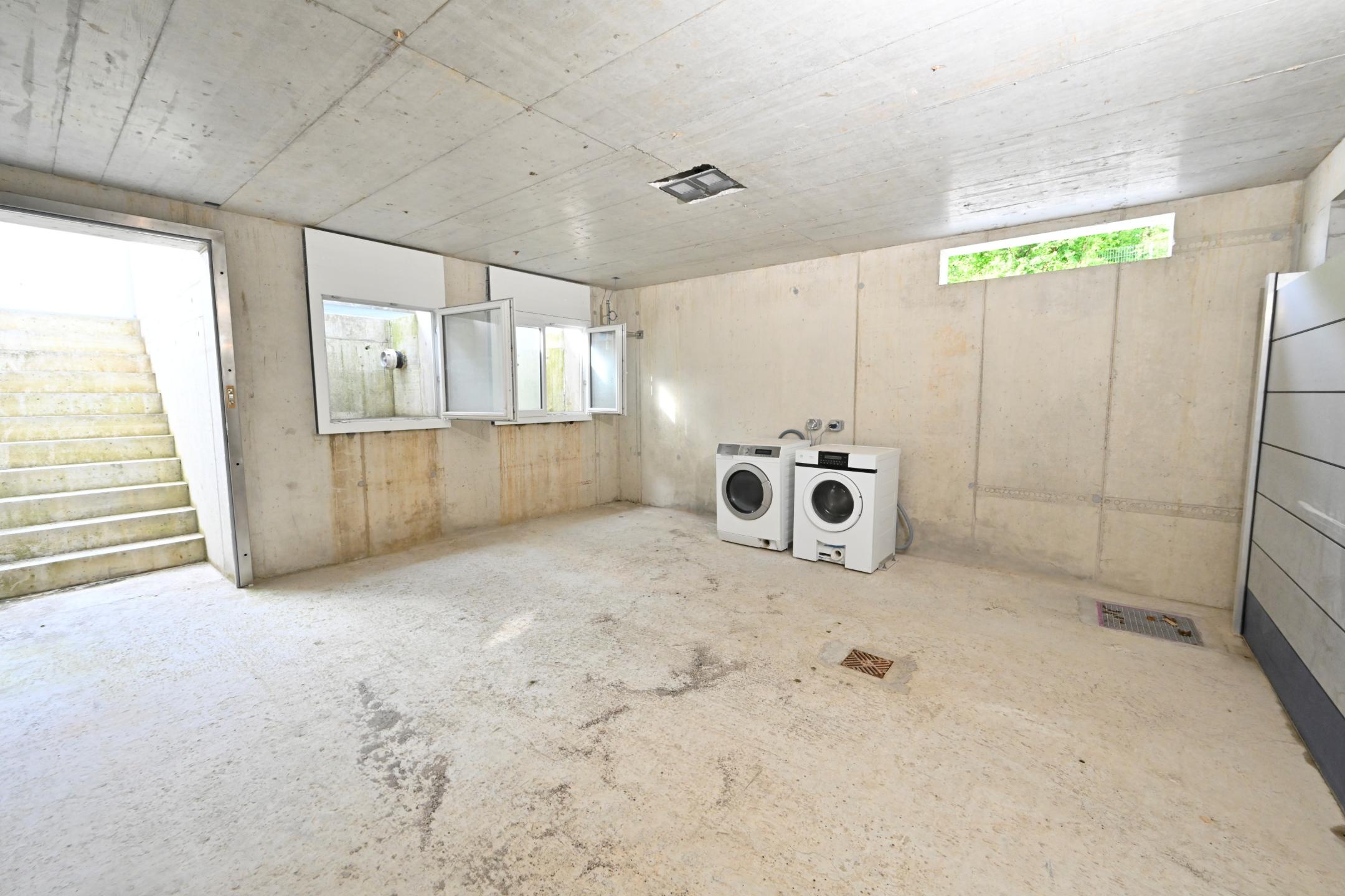 Ein heller Raum mit Treppe, Fenster und Waschmaschine und Tumbler-