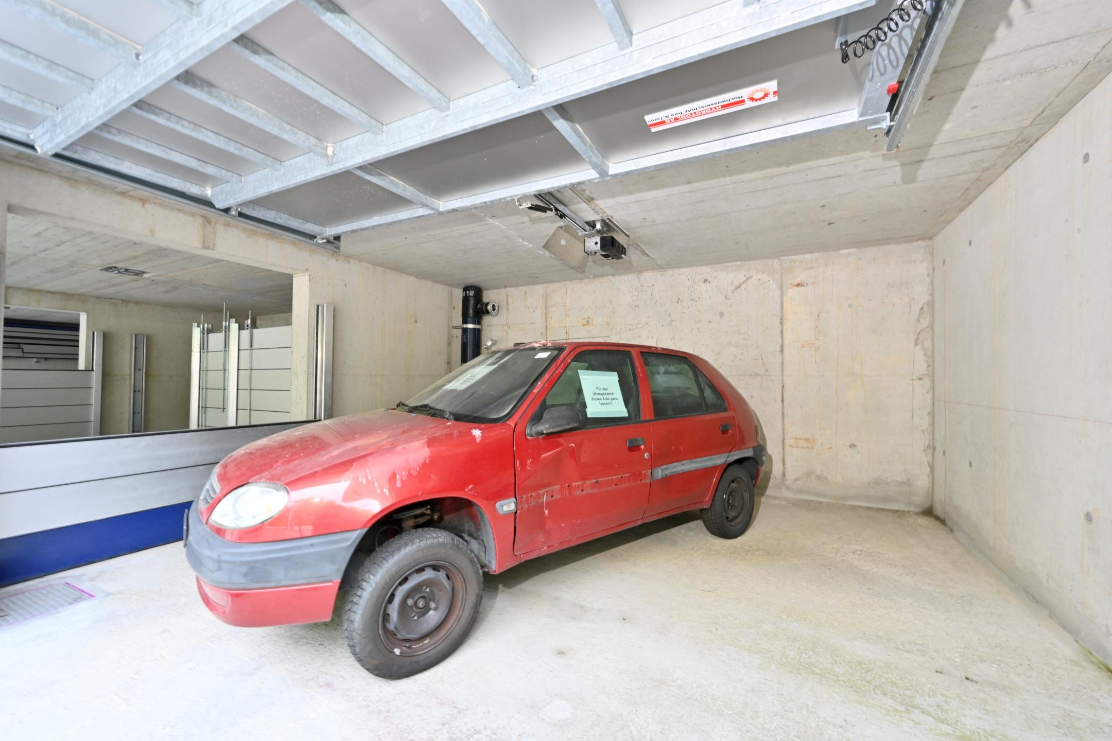 Ein Auto steht mitten im Raum der Flutungsanlage. Es ist rot und beginnt sich zu bewegen, wenn Wasser kommt.