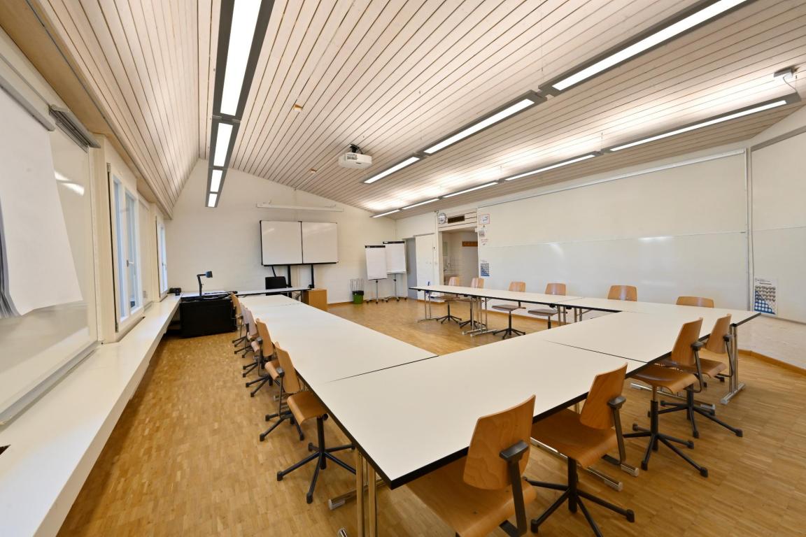 Ein klassisches Klassenzimmer mit Tischen und Bänken.