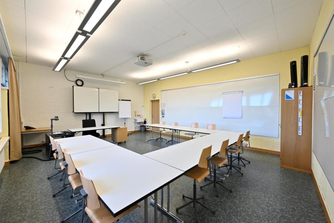 Ein klassisches Klassenzimmer mit Stühlen und Tischen.