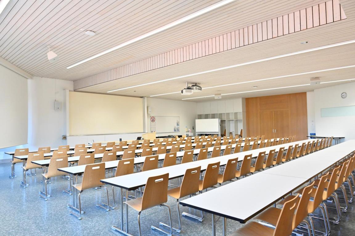 Heller Raum mit zahlreichen Tischen und Stühlen.