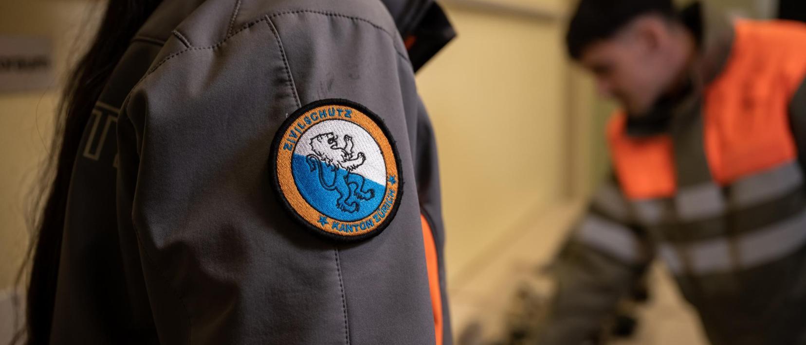 Zivilschützer sind auf einem verschwommenen Bild zu sehen. Lediglich der Zürcher Badge ist gut sichtbar.