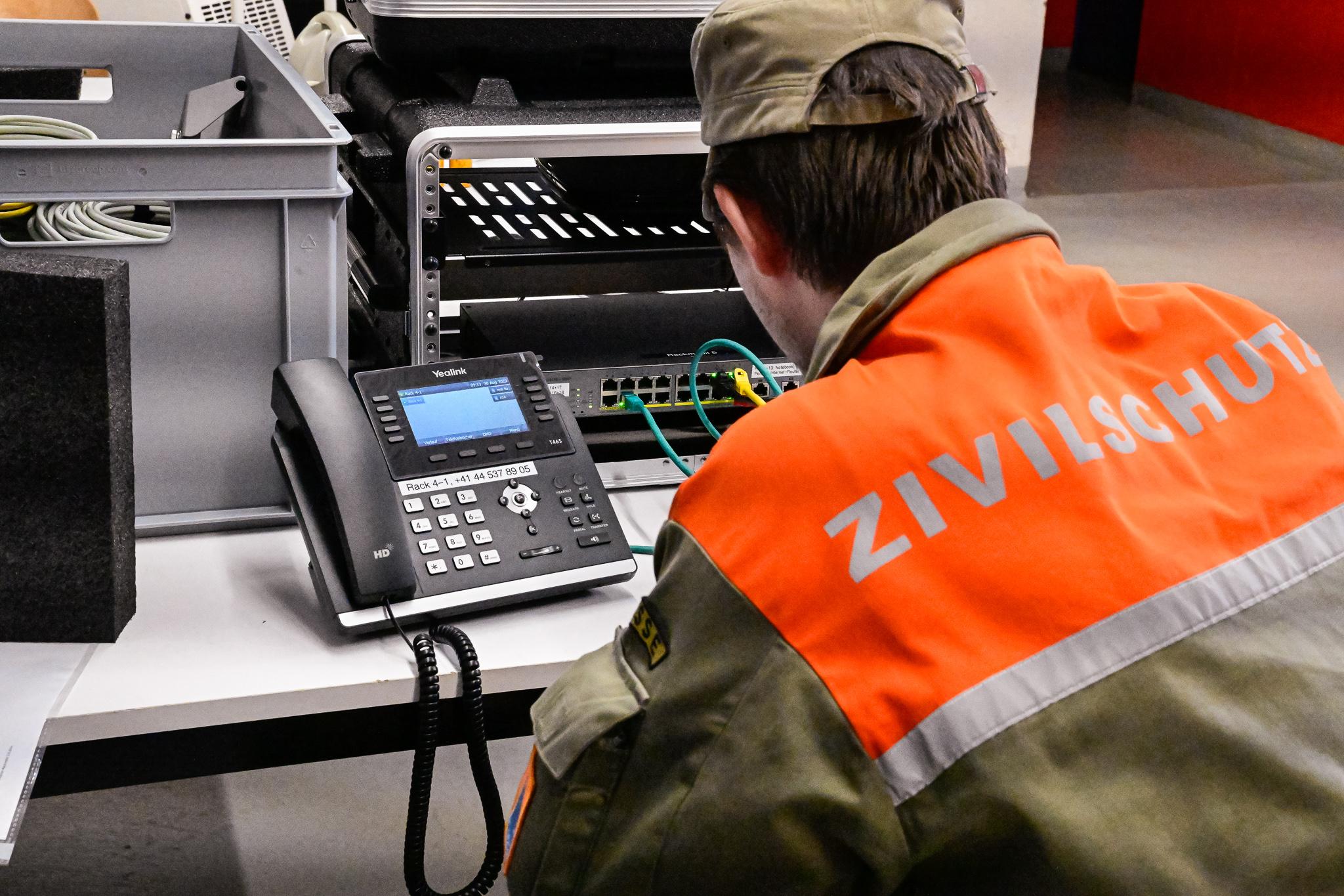 Ein Zivilschützer installiert eine Telefonanlage