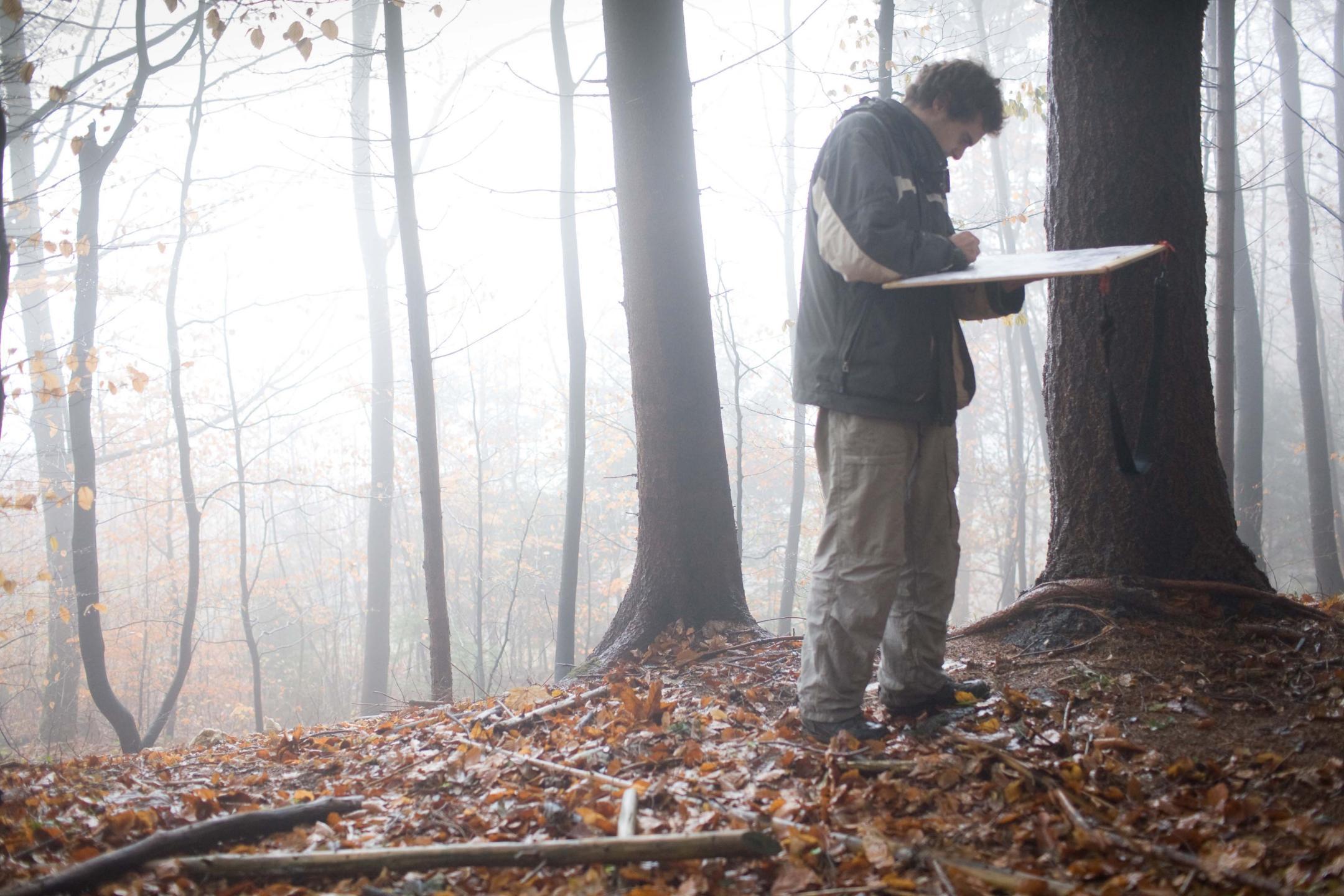 Ein Mann in einem nebligen Wald erfasst das Gebiet auf einer Karte.