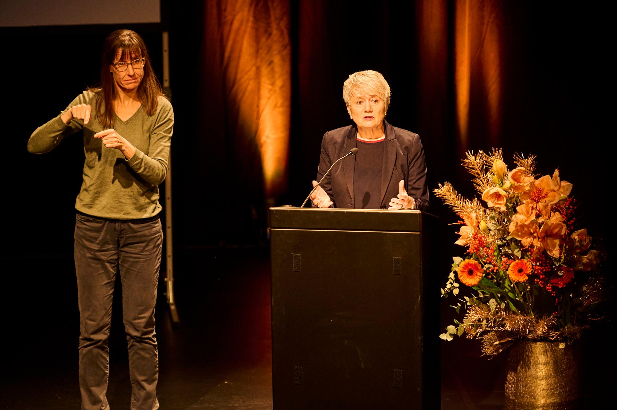 Regierungsrätin Jacqueline Fehr steht hinter Rednerpult. Daneben die Dolmetscherin für Gebärdensprache.