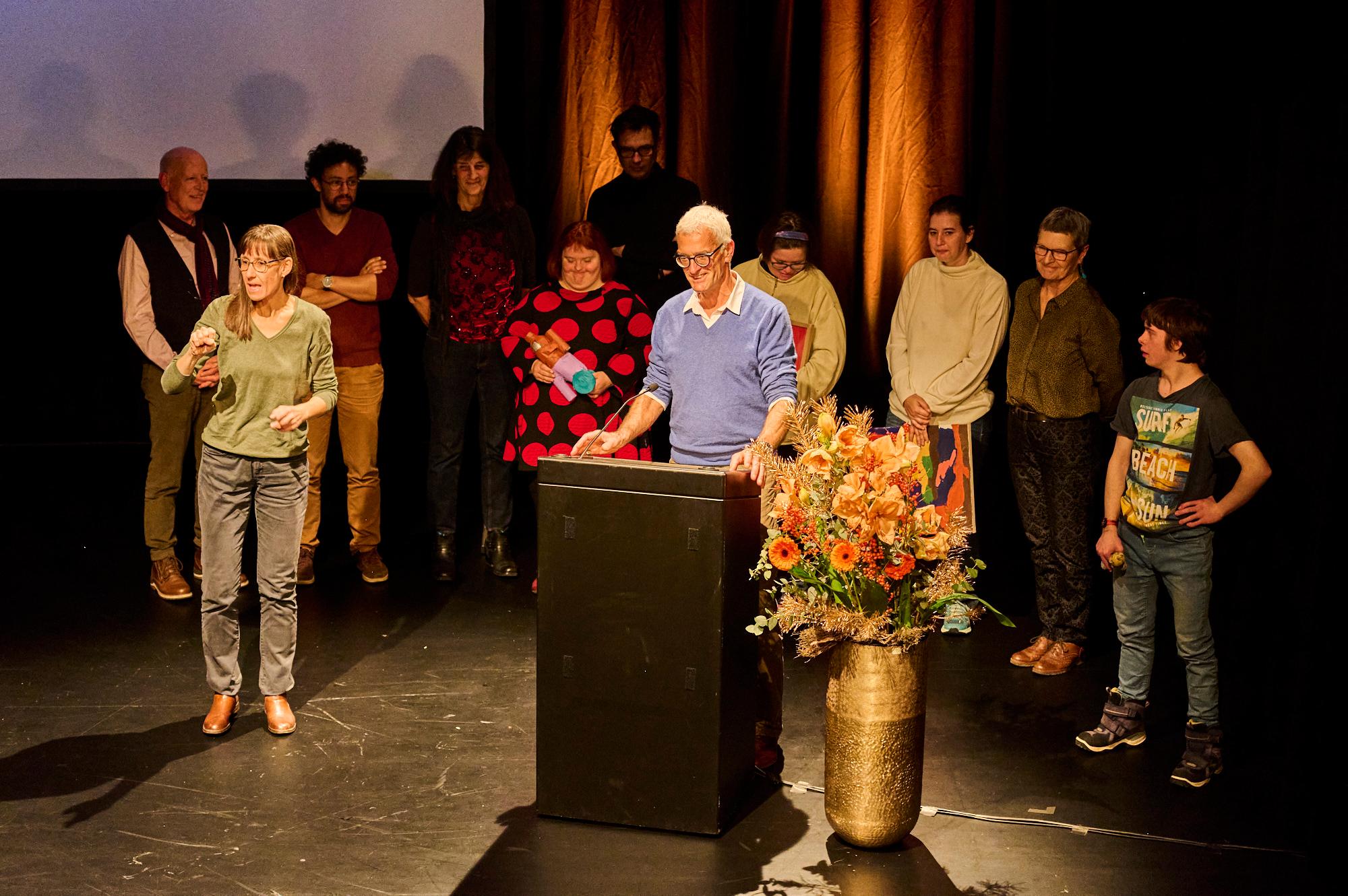 Werner Casty, hinter Rednerpult, die Gruppe von der Kunstfabrik Wetzikon im Hintergrund