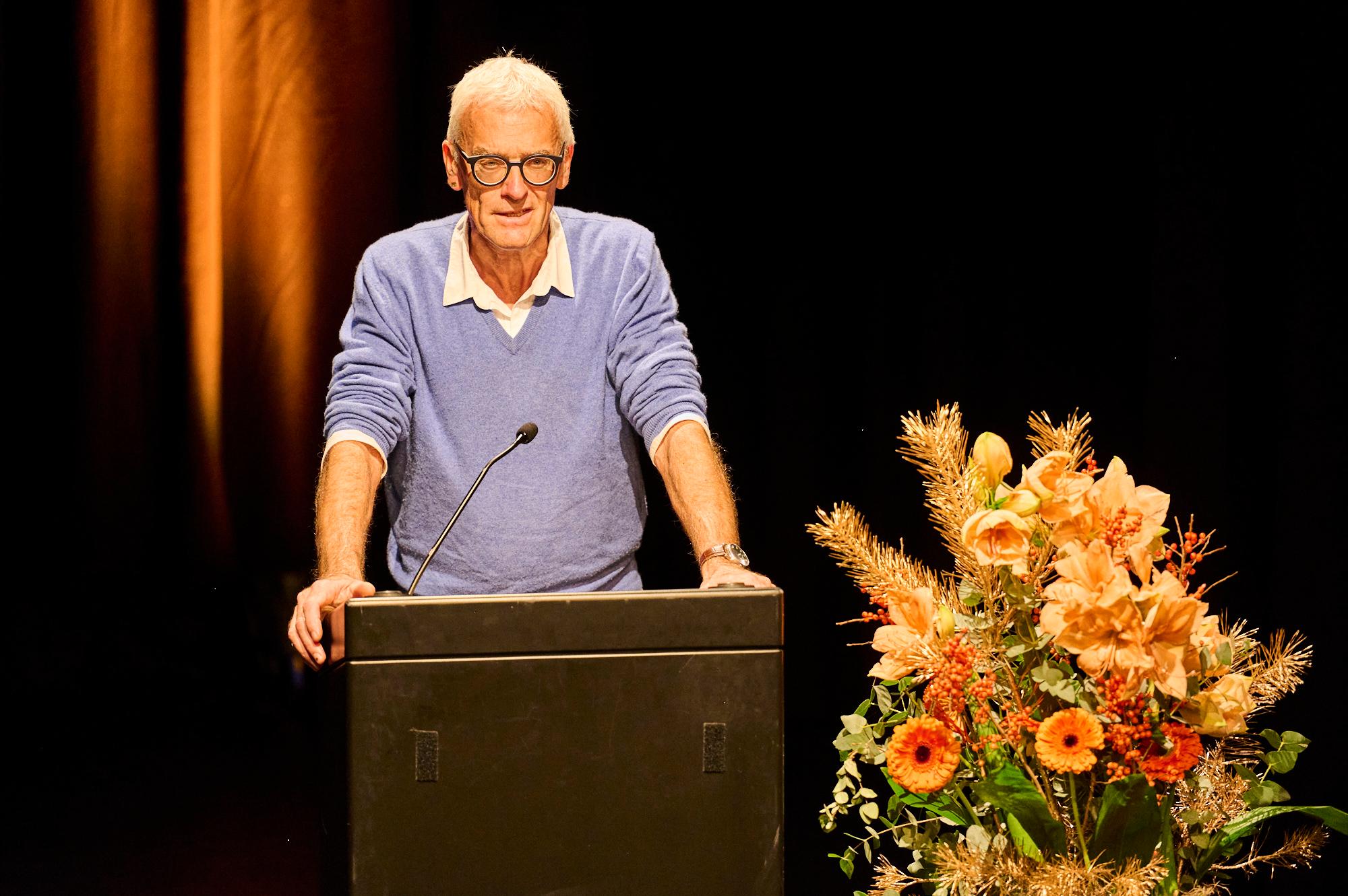 Werner Casty, hinter Rednerpult, daneben grosse Blumendeko