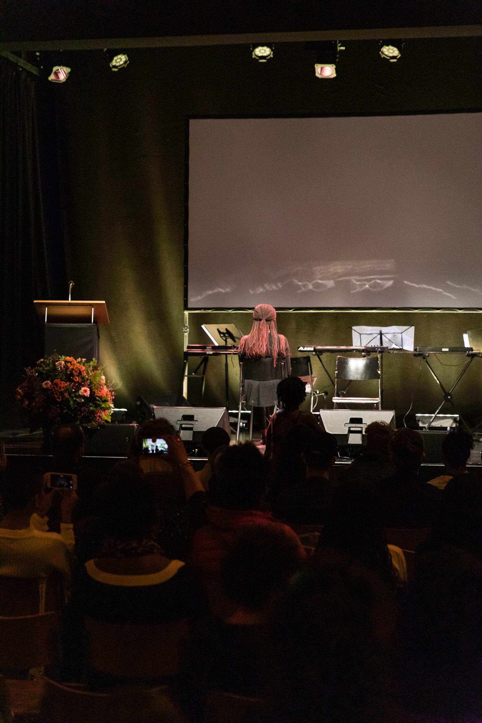 Darstellerin mit Rücken zu Publikum - liest Text