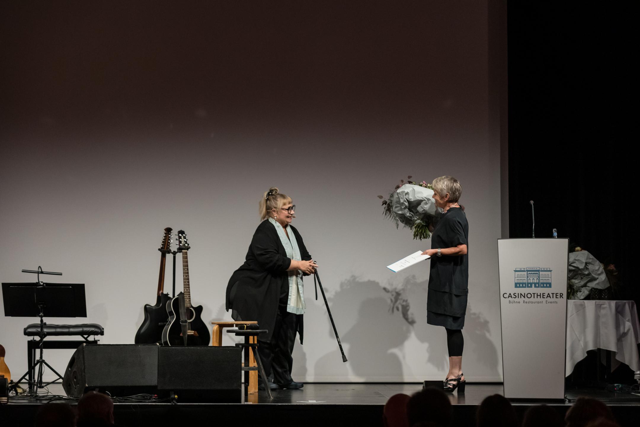 Regierungsrätin Jacqueline Fehr übergibt Blumenstrauss und Urkunde an Dodo Hug