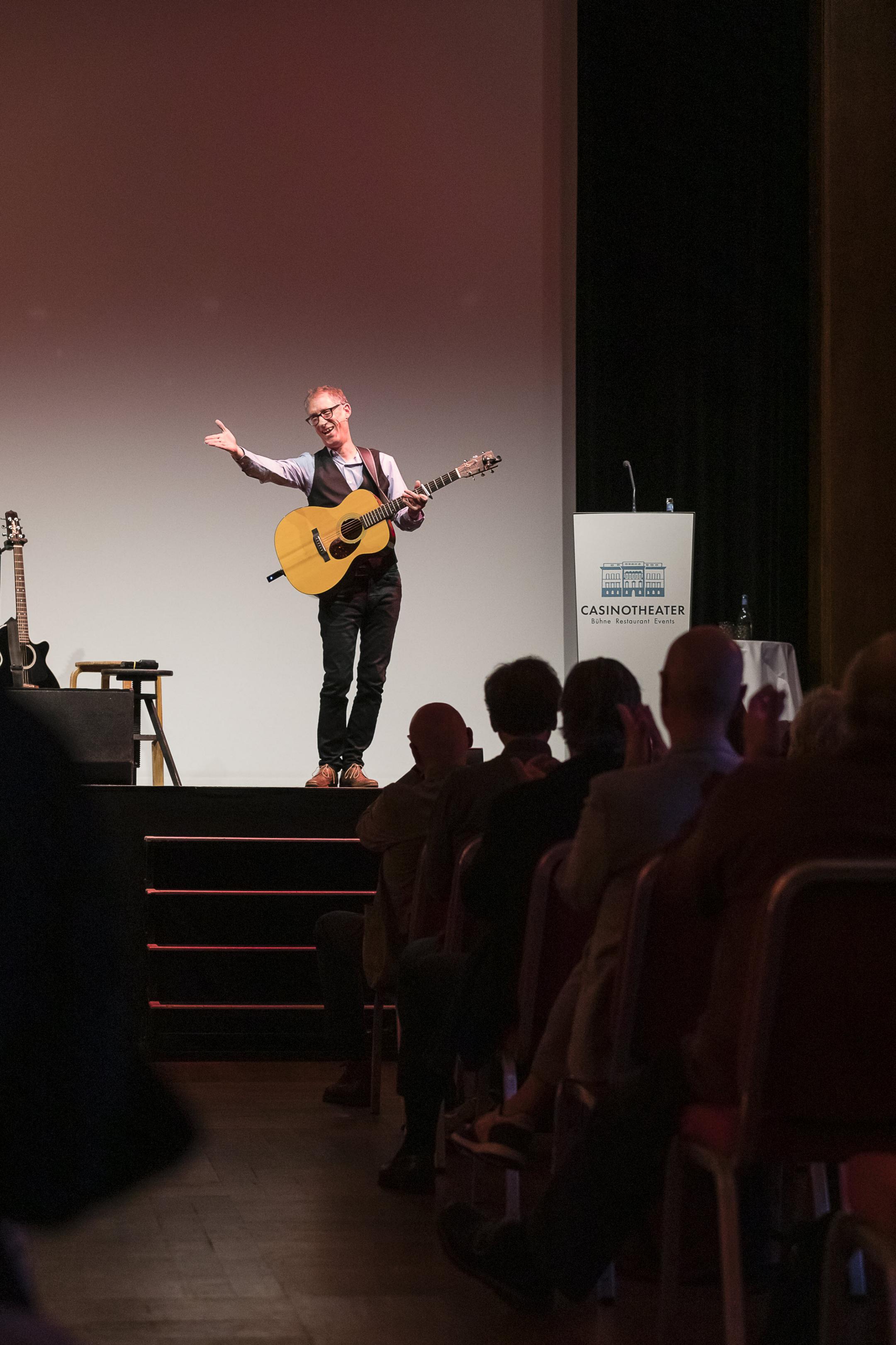 Markus Schönholzer mit Guitarre auf der Bühne