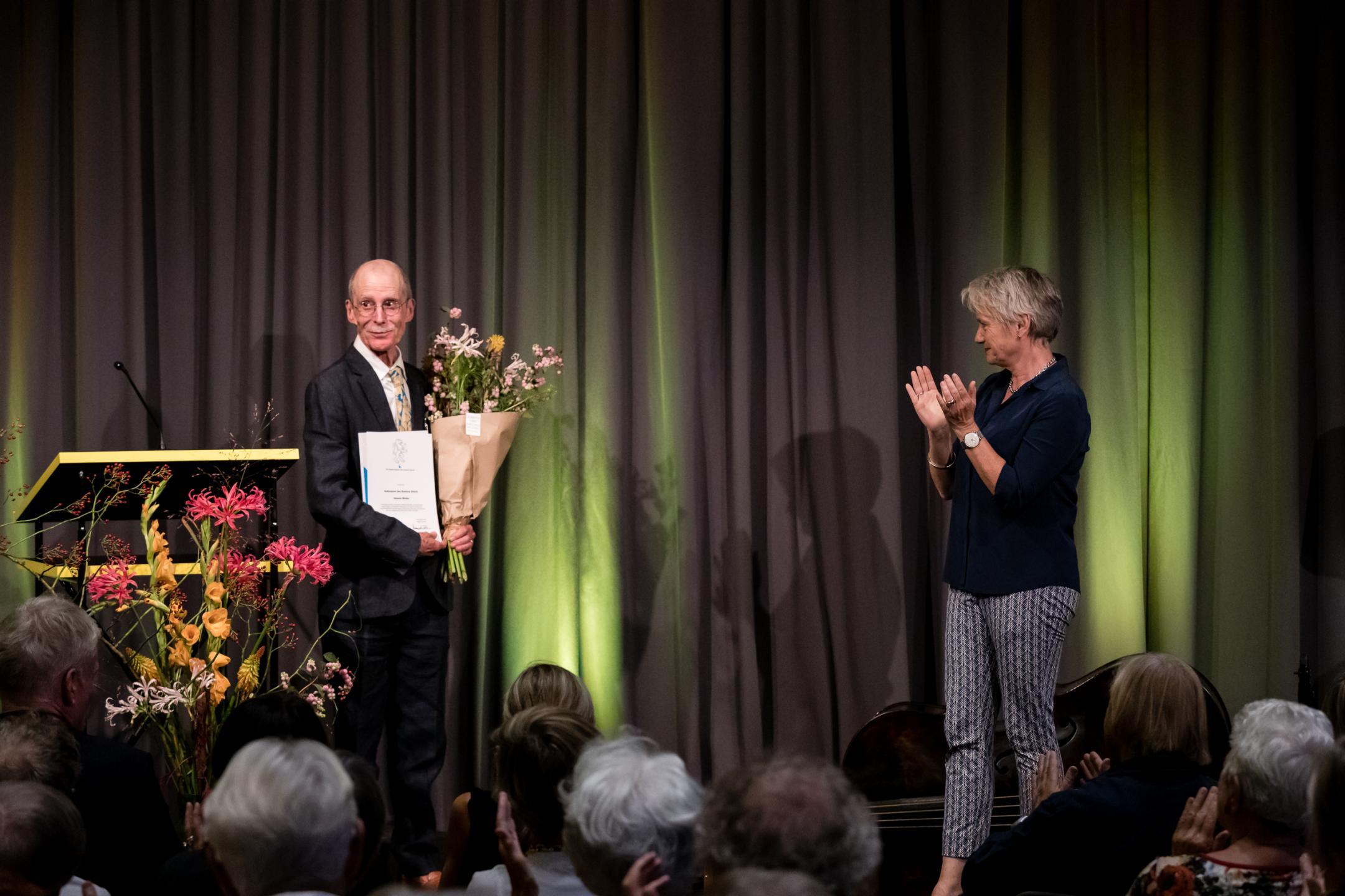 Hannes Binder mit Urkunde und Blumenstrauss, gerührt und strahlend, Jacqueline Fehr klatschend daneben