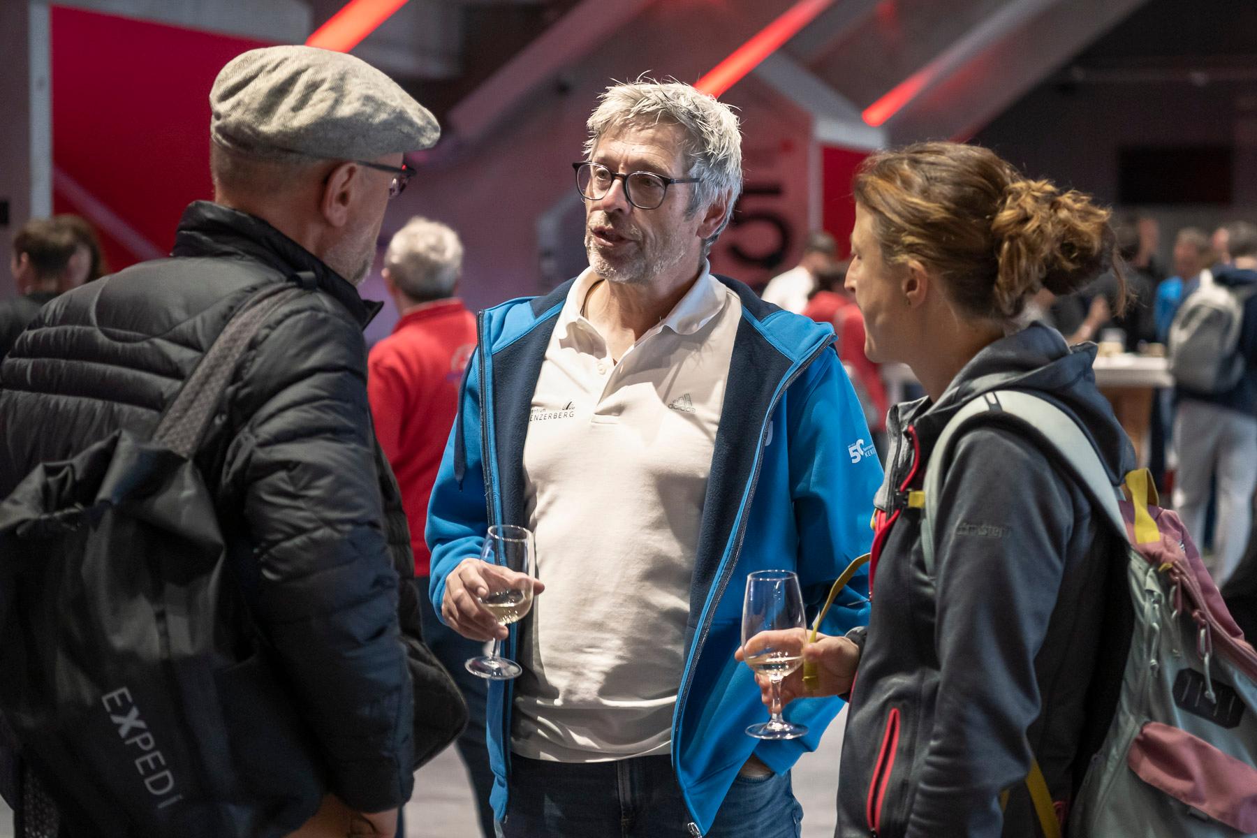 Zwei Herren und eine Frau stehen zusammen und sprechen miteinander.