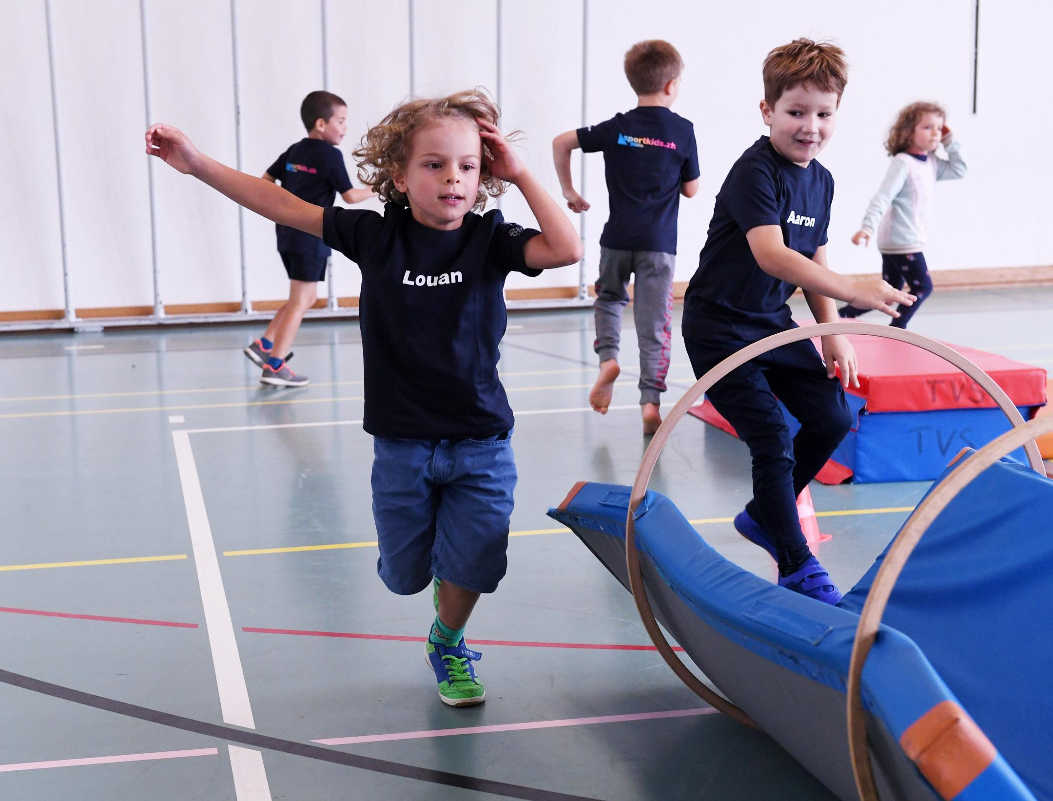 Mädchen und Knaben rennen in der Turnhalle
