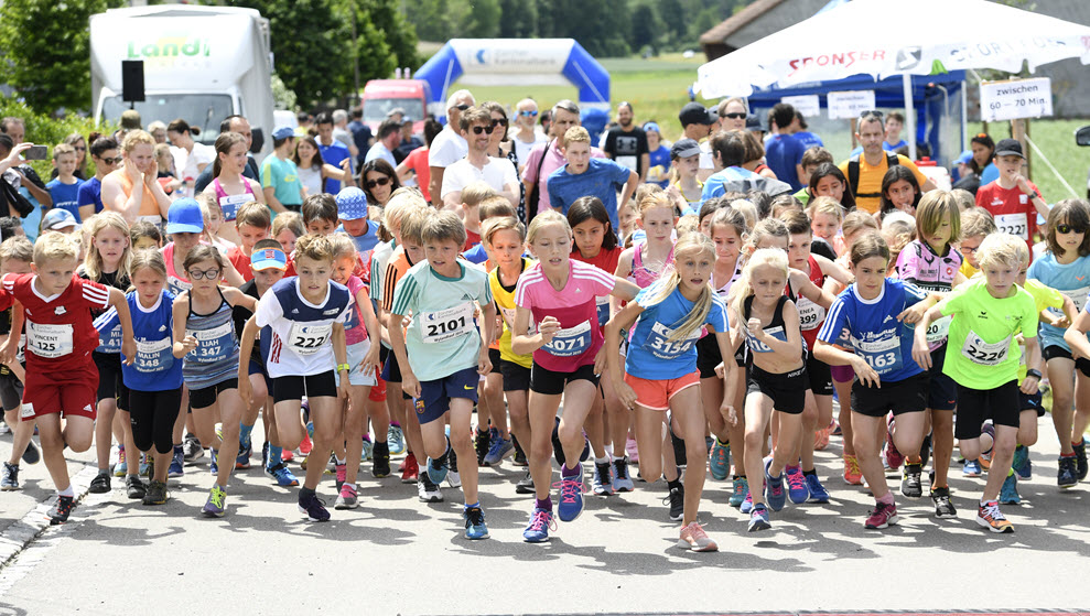 Eine Gruppe von Kindern sprintet am Start einer Laufsportveranstaltung los.