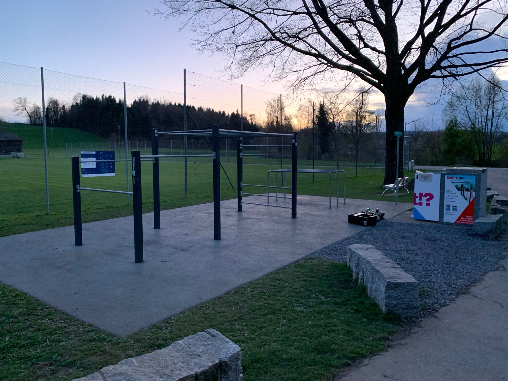 Eine SportBox (Verleihsystem mit Sport- und Fitnessequipment) steht bei einer Street Workout-Anlage vor einem Rasen in Knonau